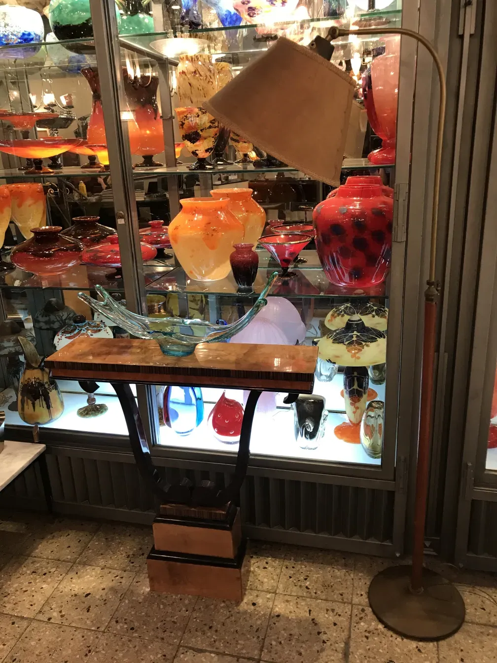 مصباح أرضي قديم مع ظل شفاف، محاط بمقتنيات عتيقة ملونة