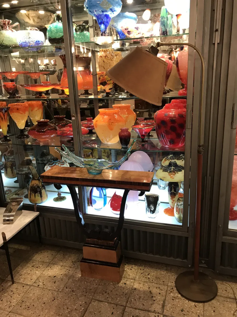 Luminária de pé antiga Art Deco em exibição entre elegantes objetos de vidro.