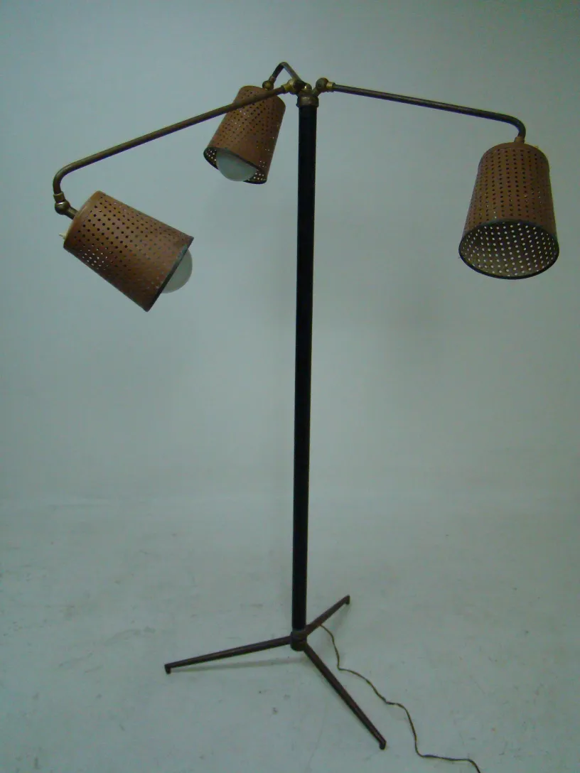 Une lampe de sol ancienne de style Art Deco, avec deux abat-jours perforés en forme de tunnel, dans un cadre minimaliste.