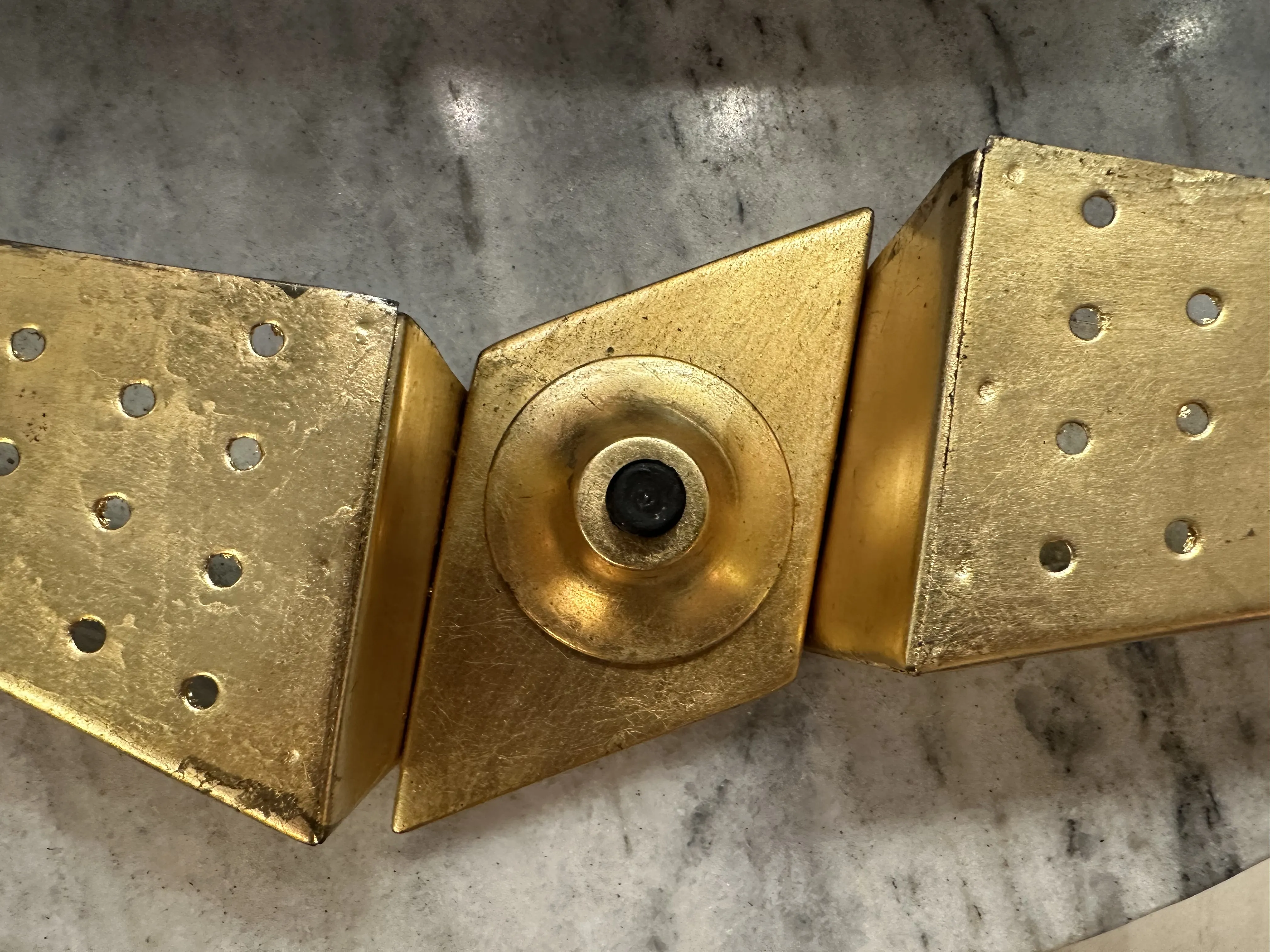 Antike Wandleuchte mit geometrischem Design und goldener Oberfläche, ideal zur Dekoration.