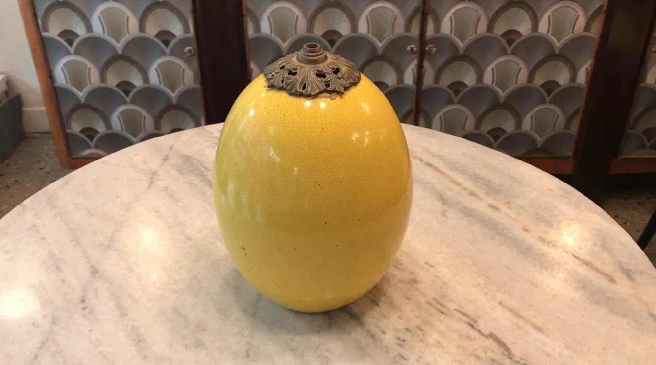 Antique art deco yellow table lamp, oval shape and elegant, placed on a marble table.