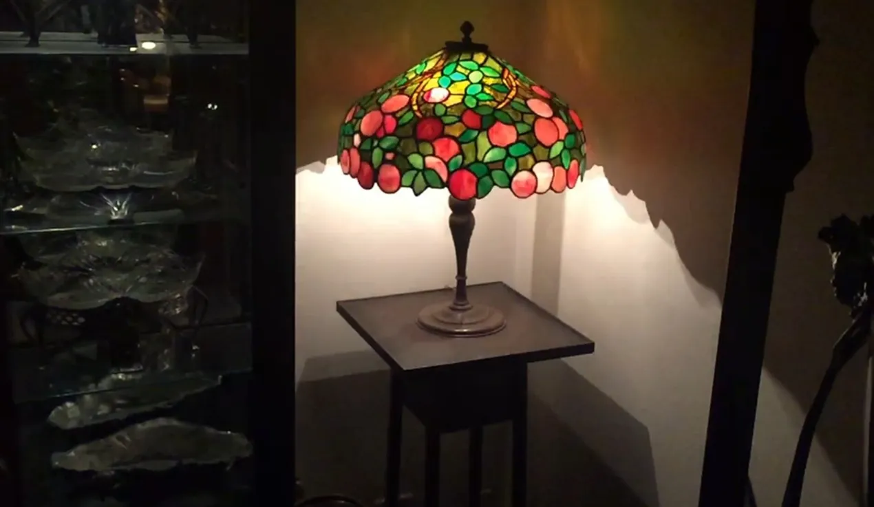 Lámpara de mesa antigua con pantalla de colores brillantes y diseño art deco.