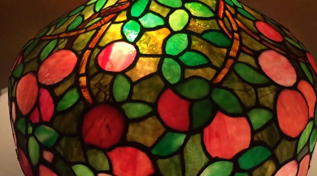 Luminária de mesa antiga Art Deco com design de folhas verdes e rosas, cria um ambiente acolhedor.