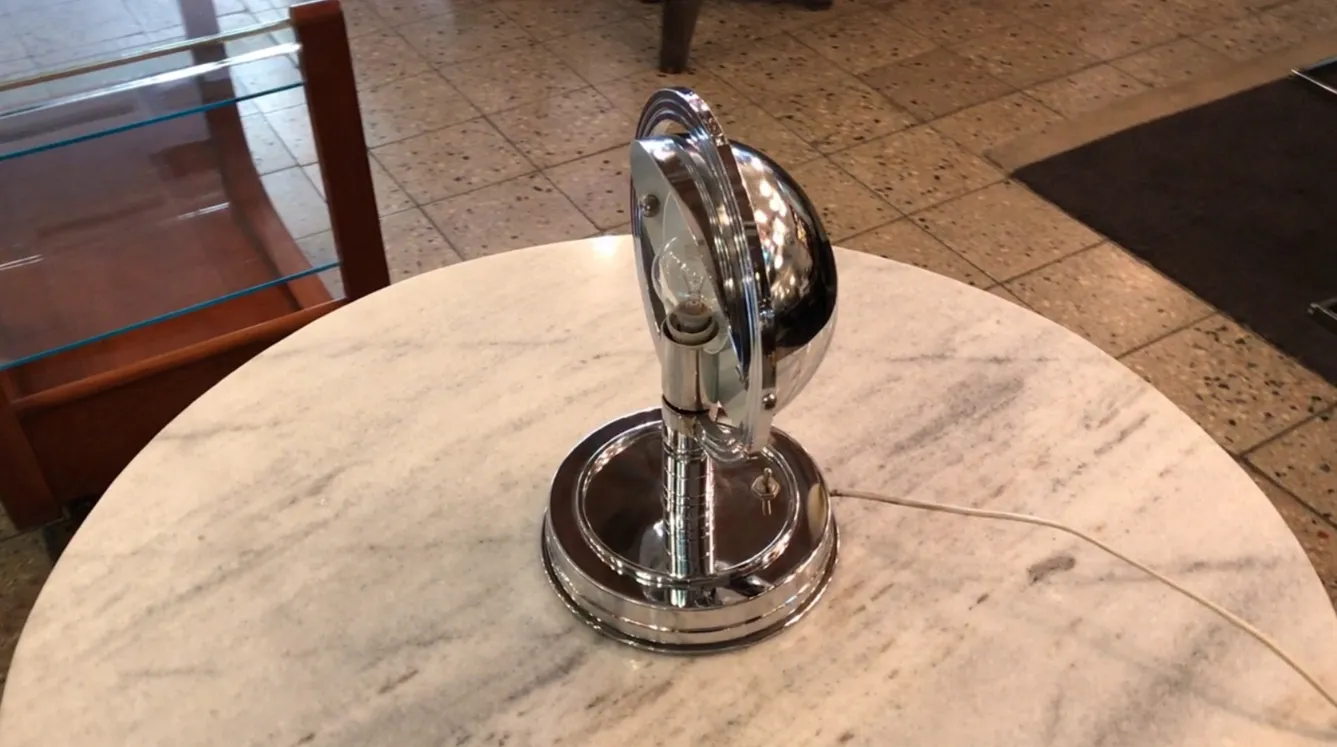 Lampe de bureau ancienne avec un design brillant en chrome, entourée d'un environnement chaleureux.