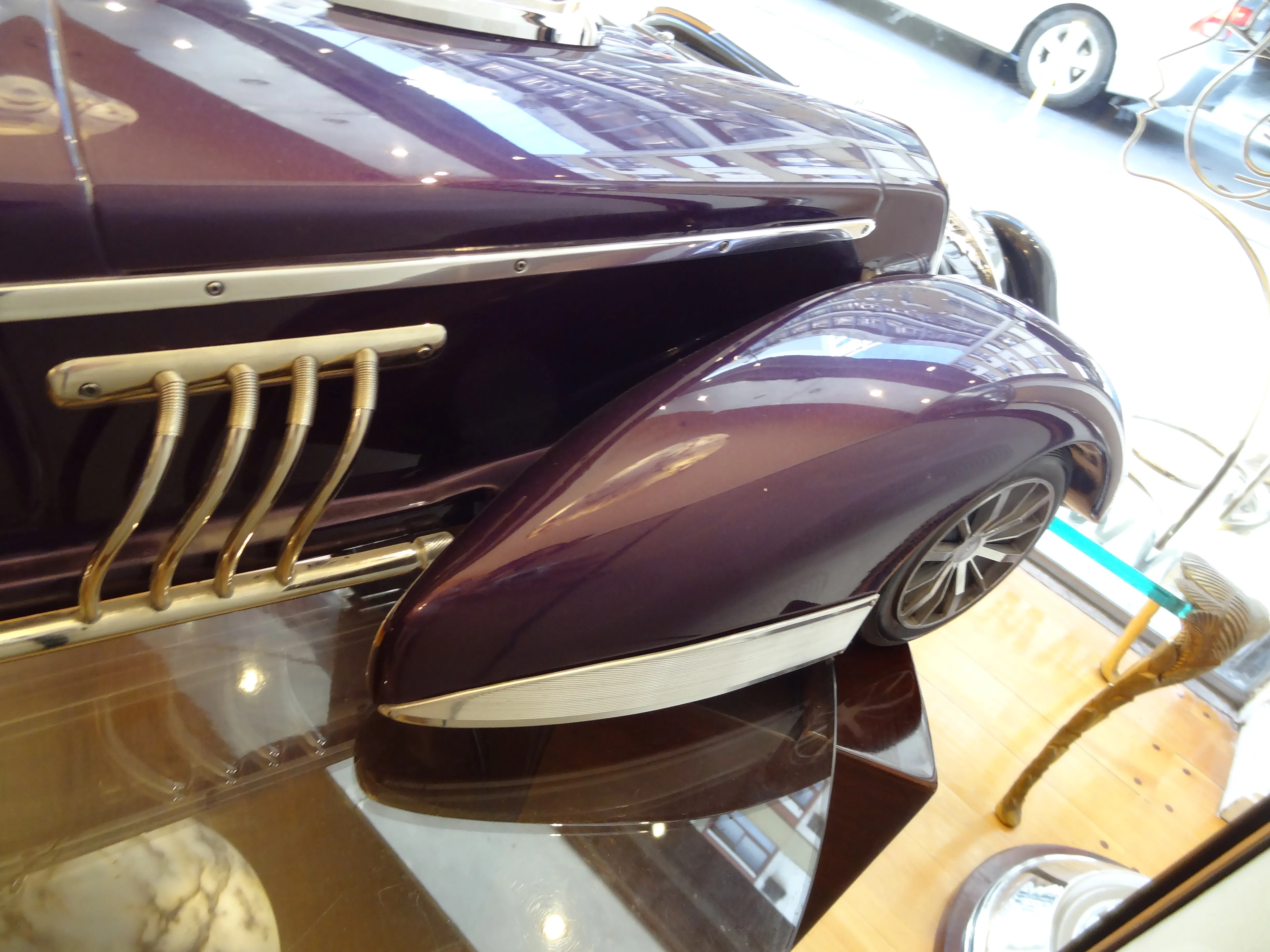 Vista laterale di un elegante auto antica in mostra, con dettagli dorati e colore viola.