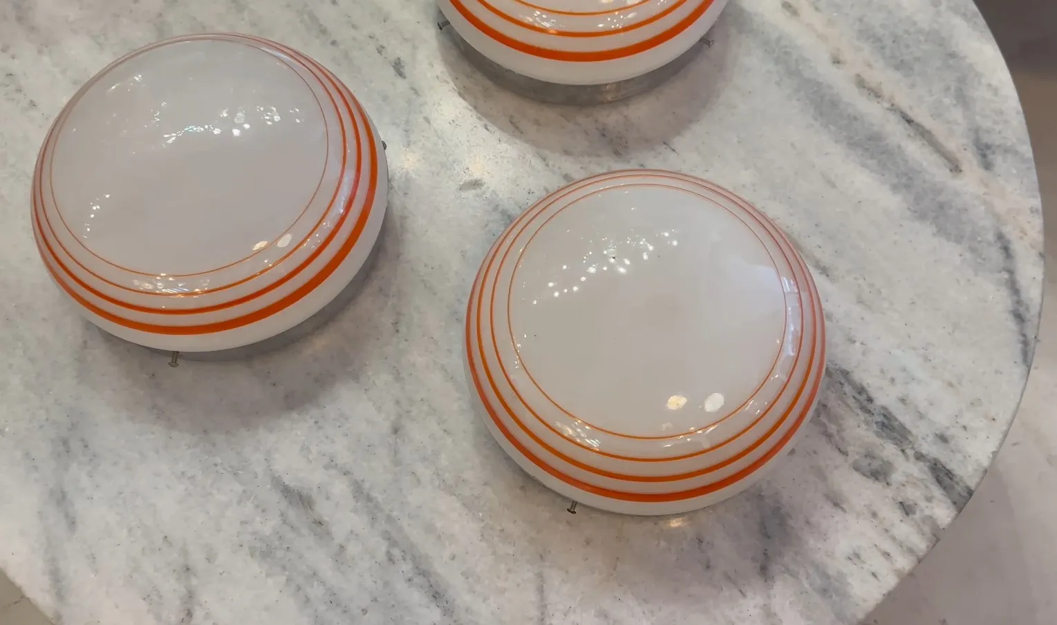 three antique round ceiling lights with orange stripes, on a light marble background