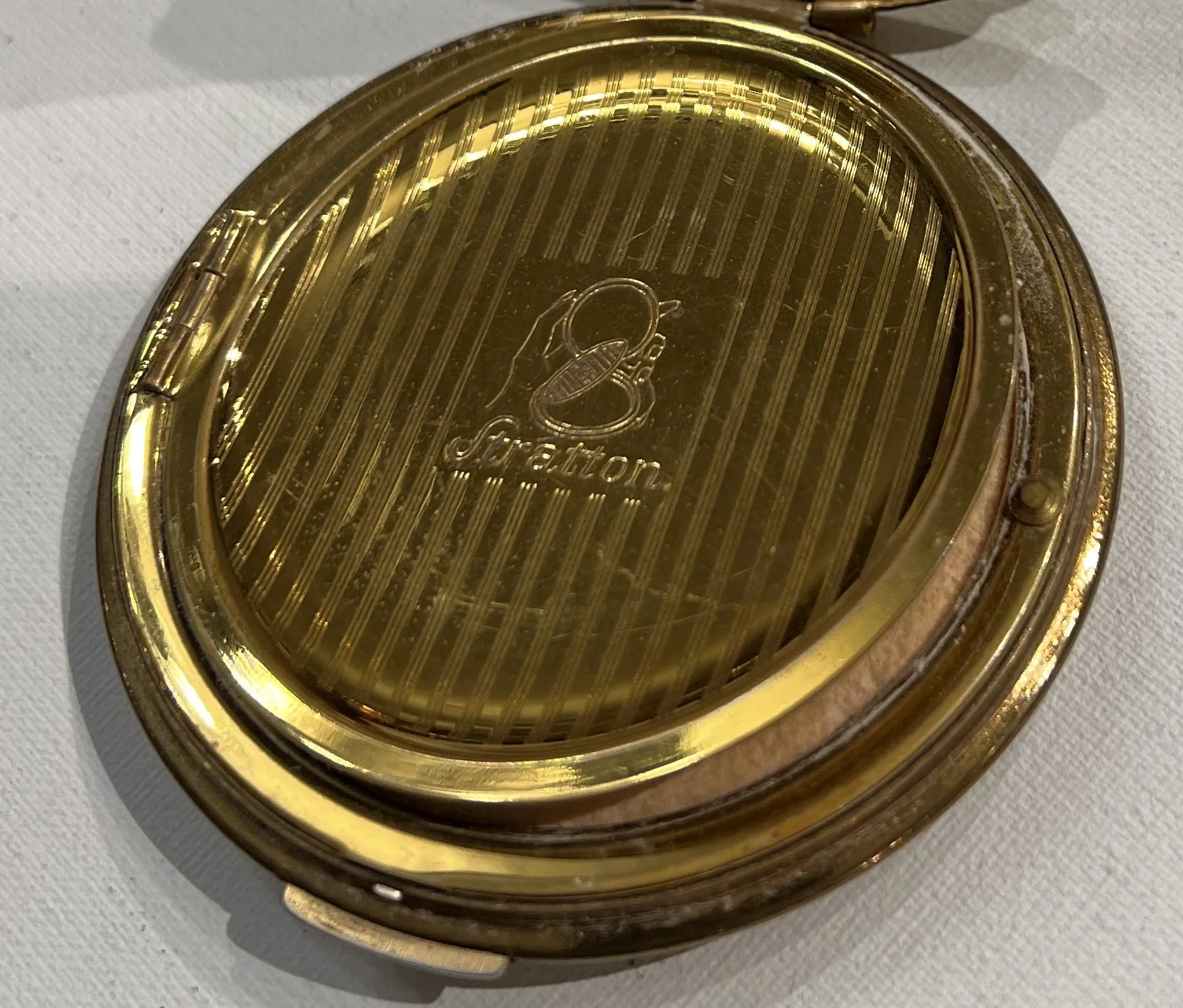 Antique compact with elegant Stratton England design, gold background.