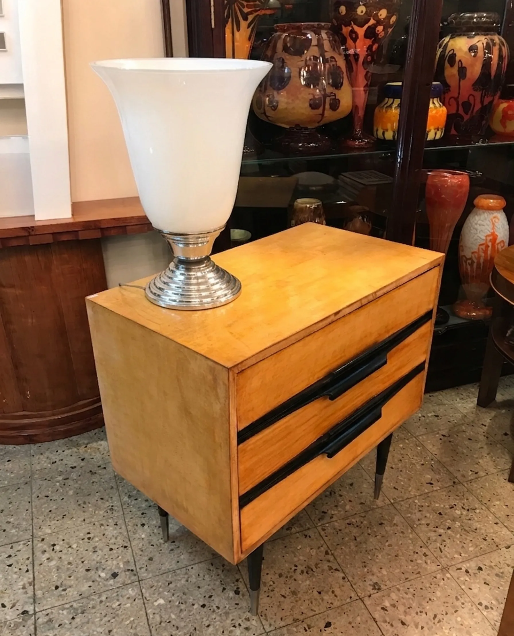 lampada de mesa antiga com base metalica e shade branco em uma mesa de madeira