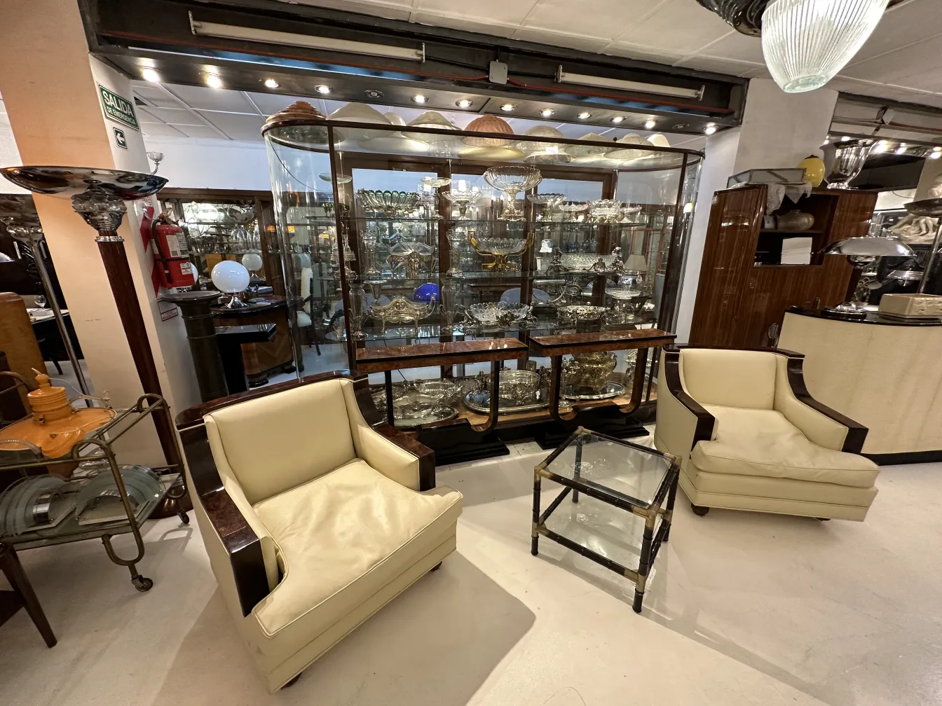 Três mesas de centro antigas em um ambiente elegante com cadeiras