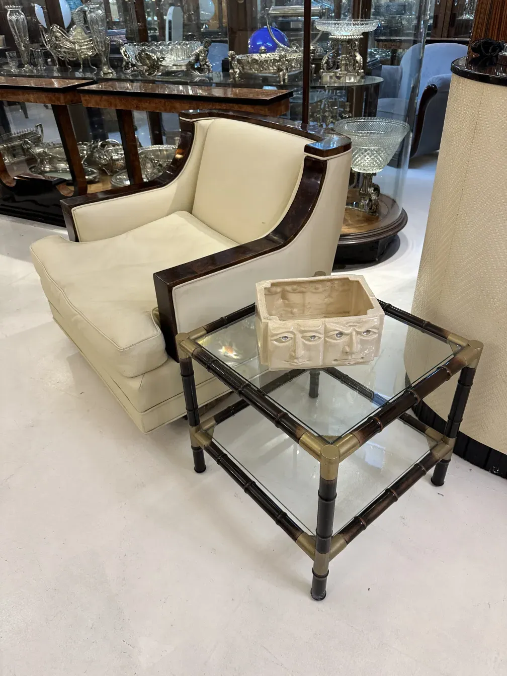 Trois tables basses antiques à côté d'un fauteuil blanc et d'objets décoratifs