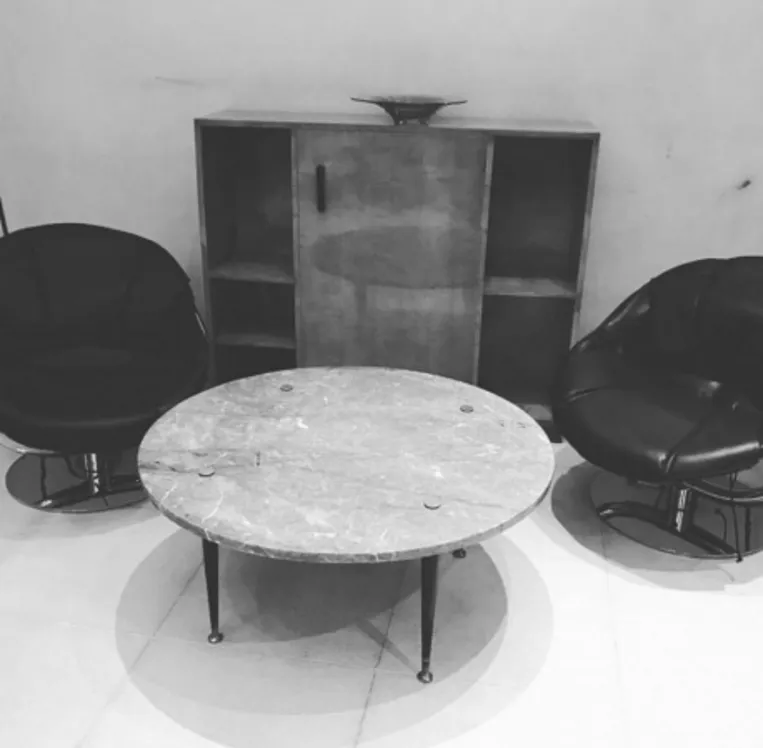 mesa ratona antigua de forma redonda con sillones negros