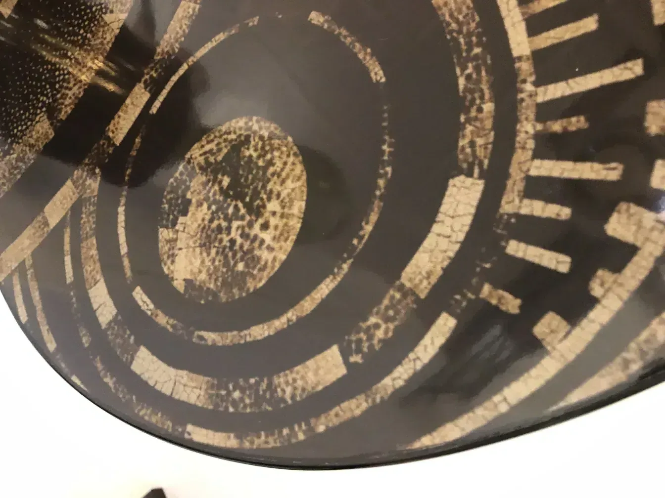 Tavolino antico con motivi geometrici chiari e scuri.