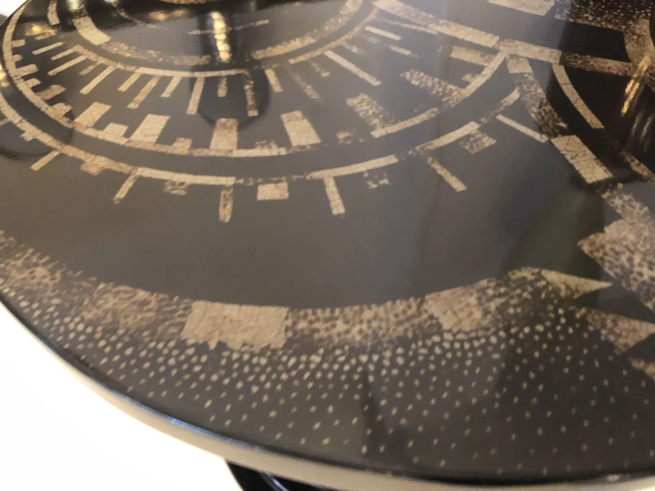 Antique decorative small table with black surface and patterns.