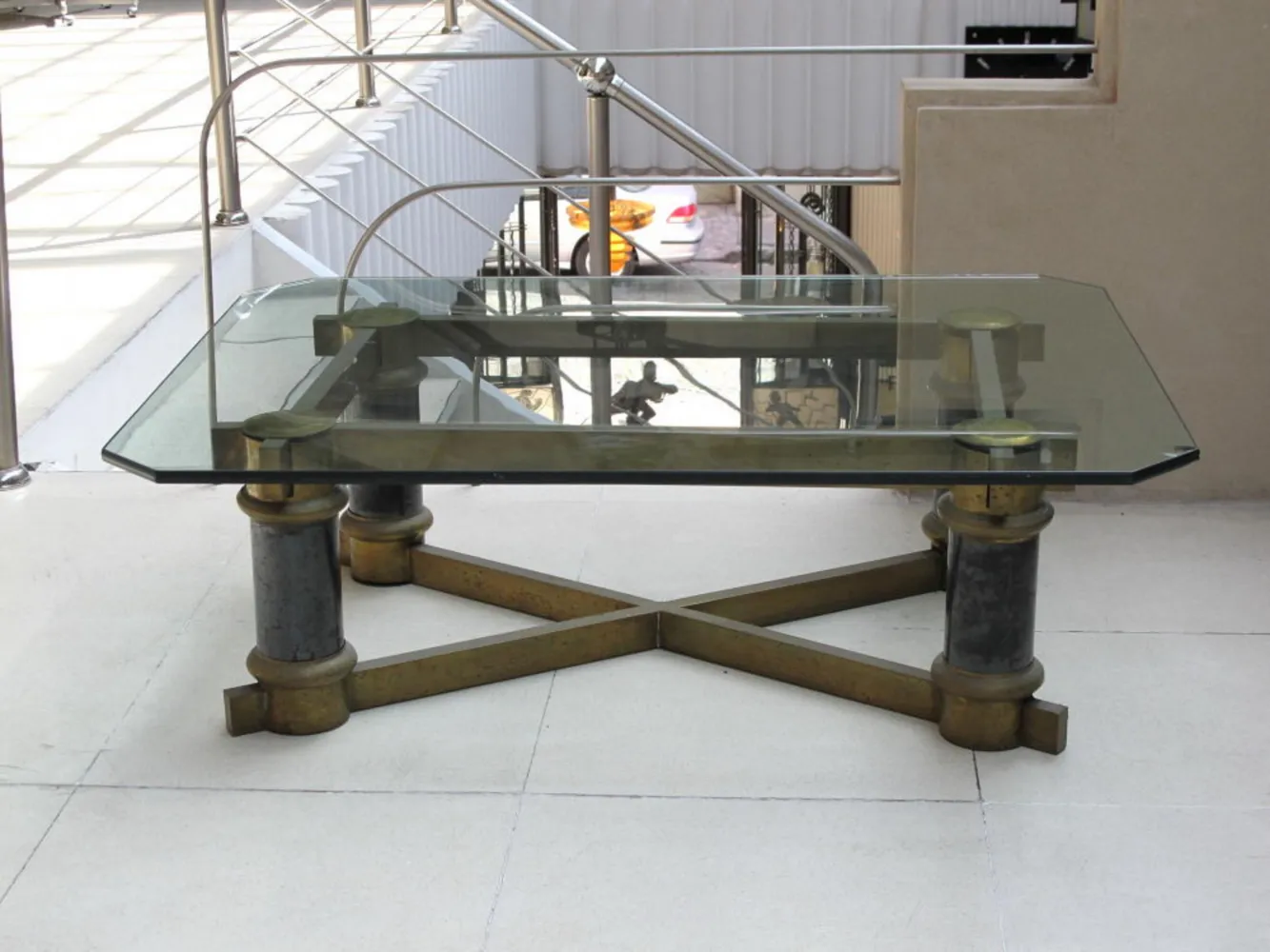 Table basse ancienne avec dessus en verre et pieds décoratifs dans un cadre moderne.