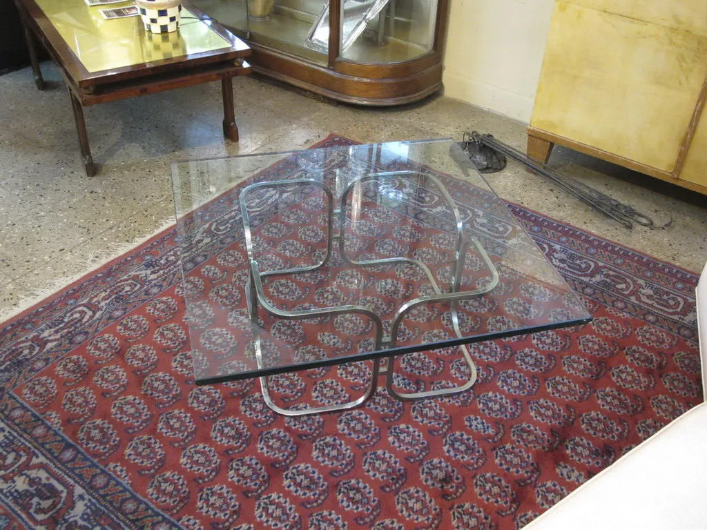 Antique coffee table with glass top and metal base, set in a cozy environment.