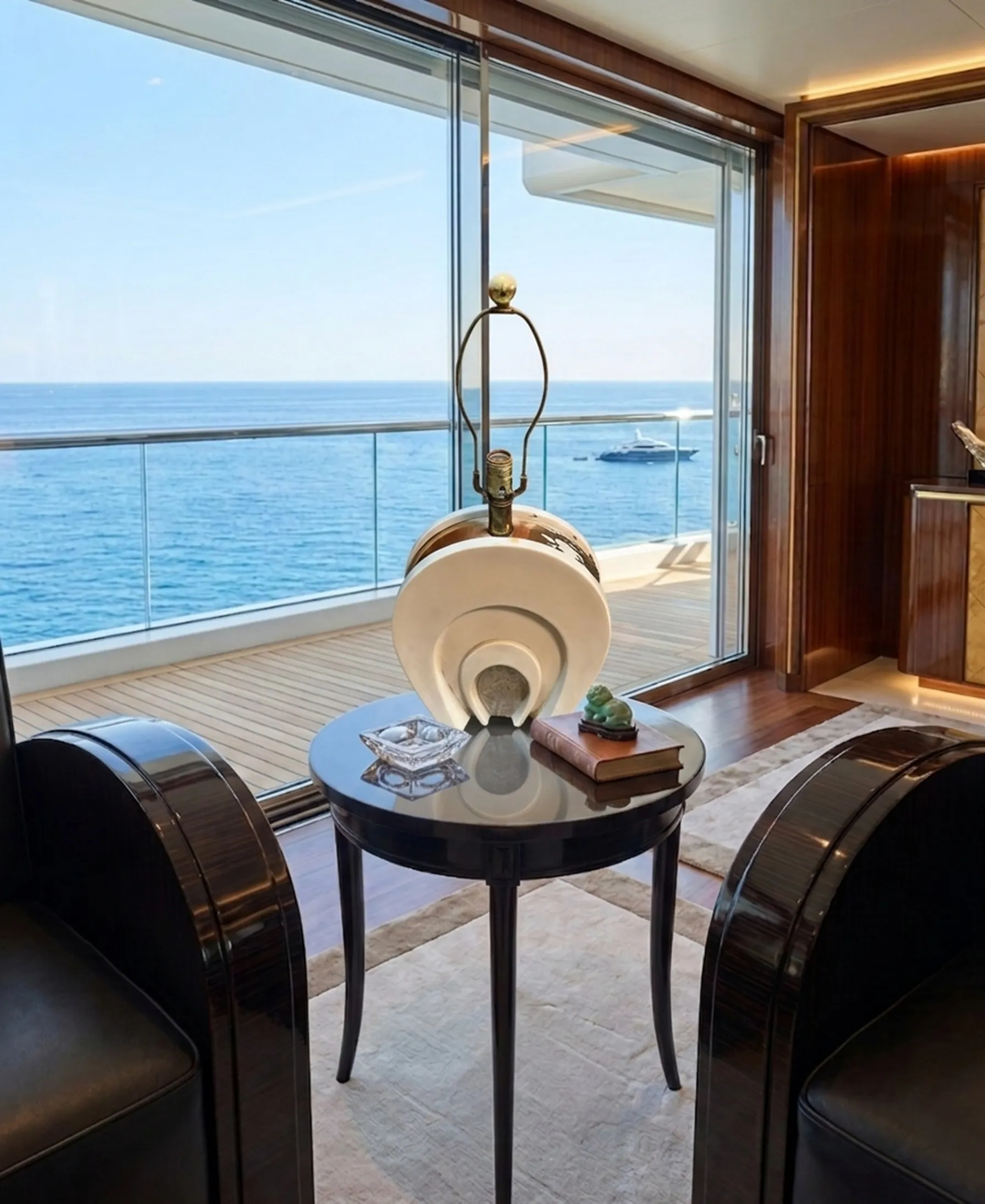 Mesita antigua pequeña en un ambiente marino con vista al mar y otros objetos decorativos.