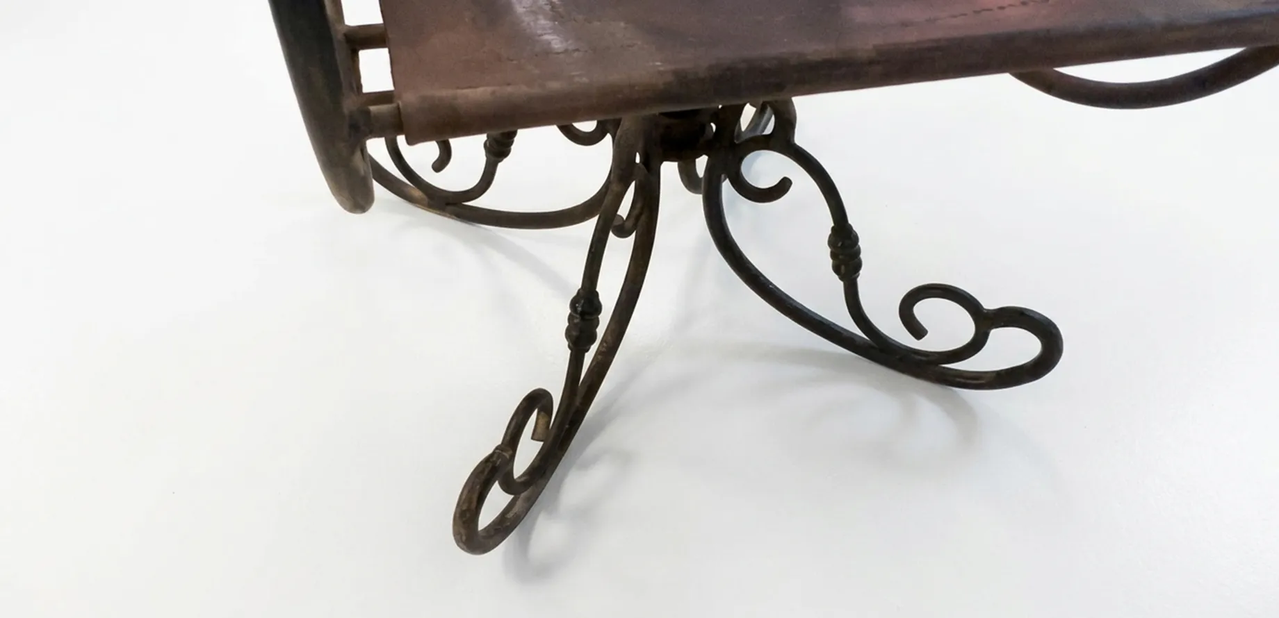 Sillón antiguo con patas curvas y detalles ornamentales en un entorno neutral