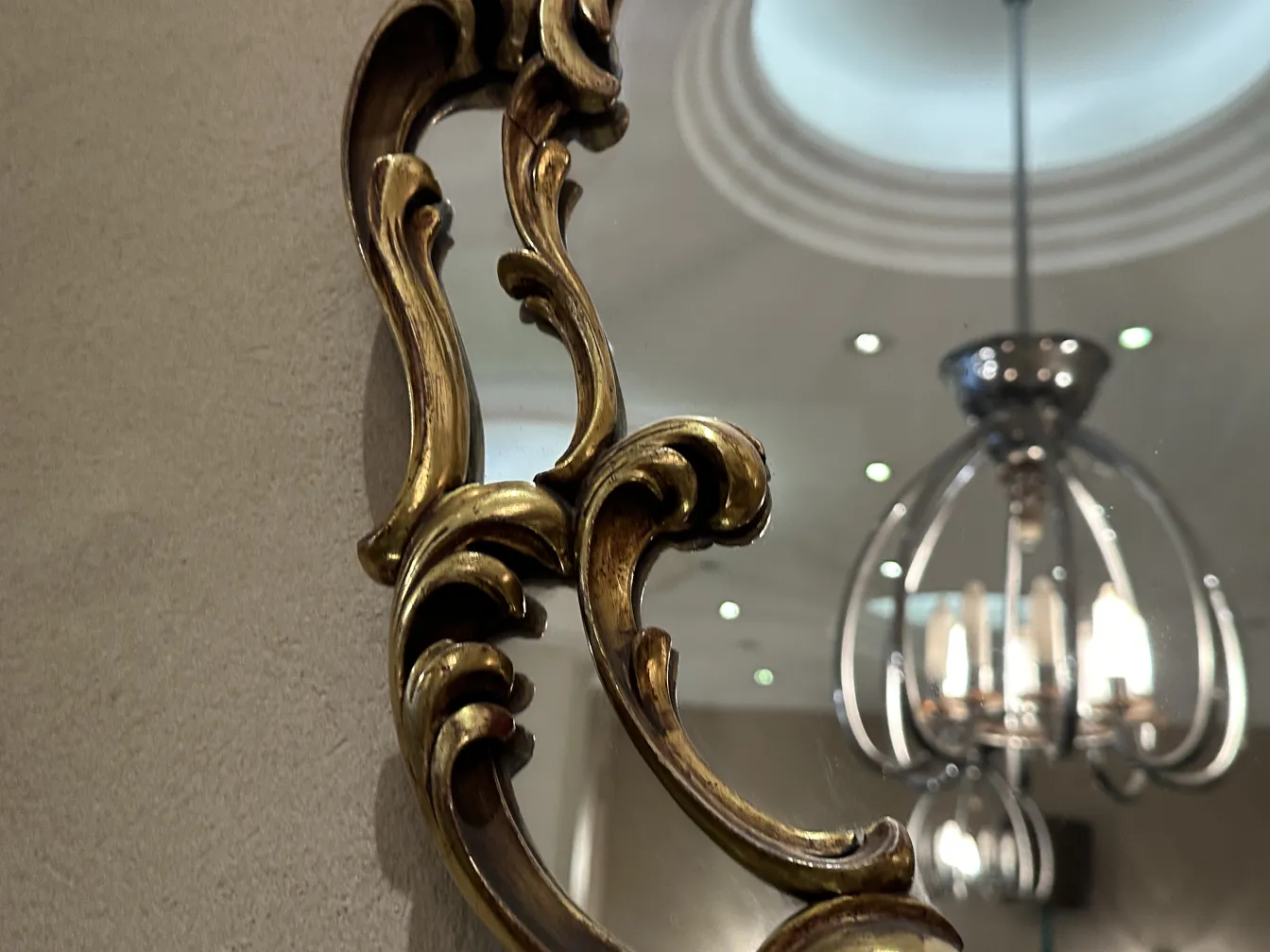 Miroir ancien avec cadre décoratif et fond neutre.