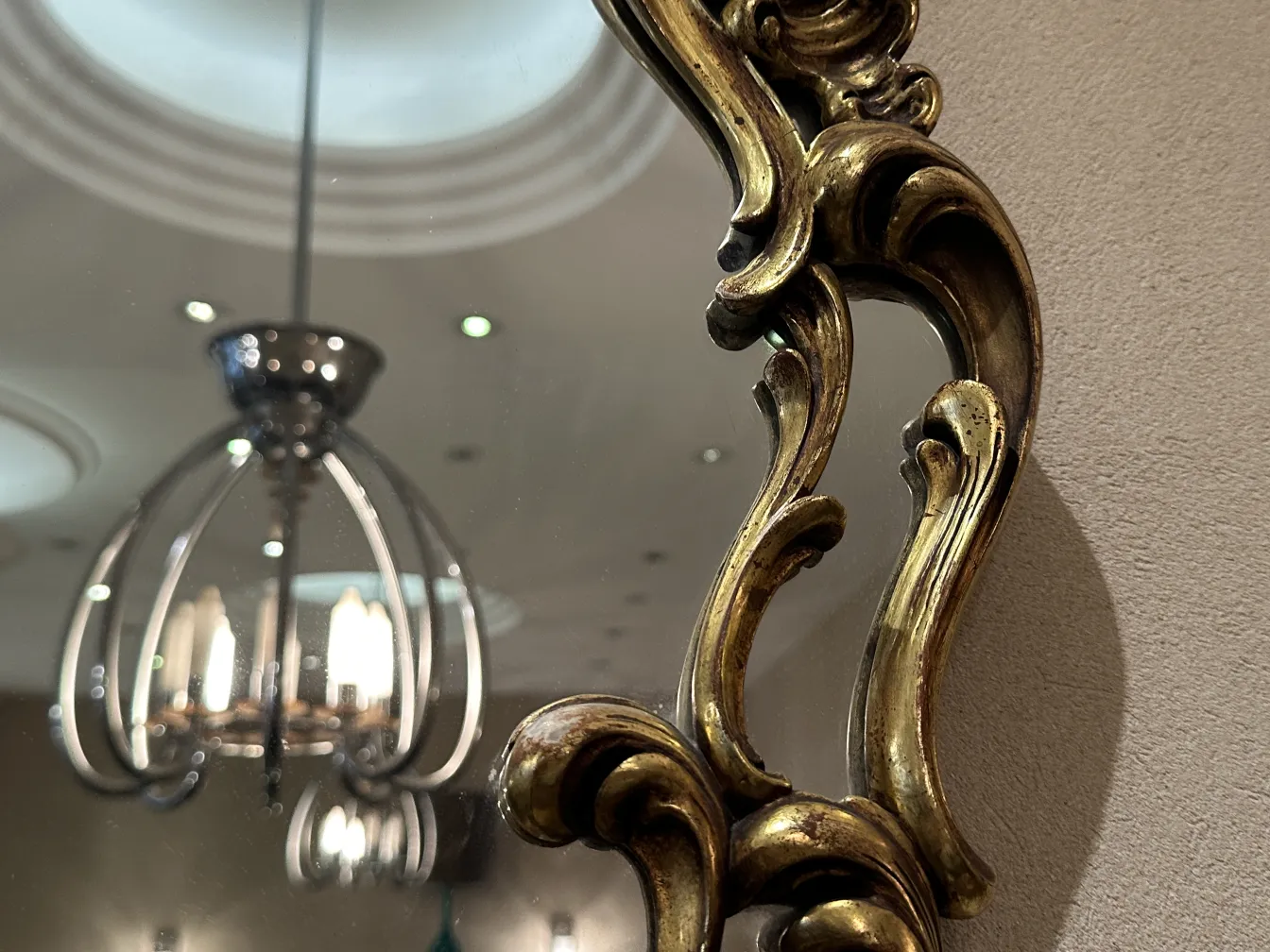 specchio antico con cornice ornata e luce riflessa