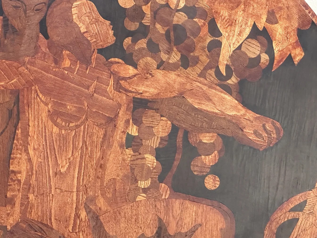 Detail of antique marquetry with human figures and decorative elements.