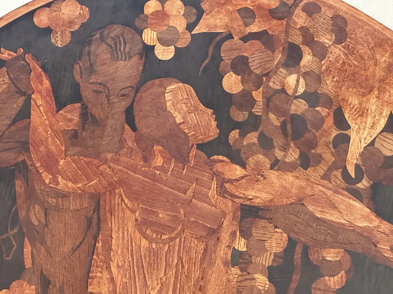 Antique marquetry featuring human figures surrounded by foliage.