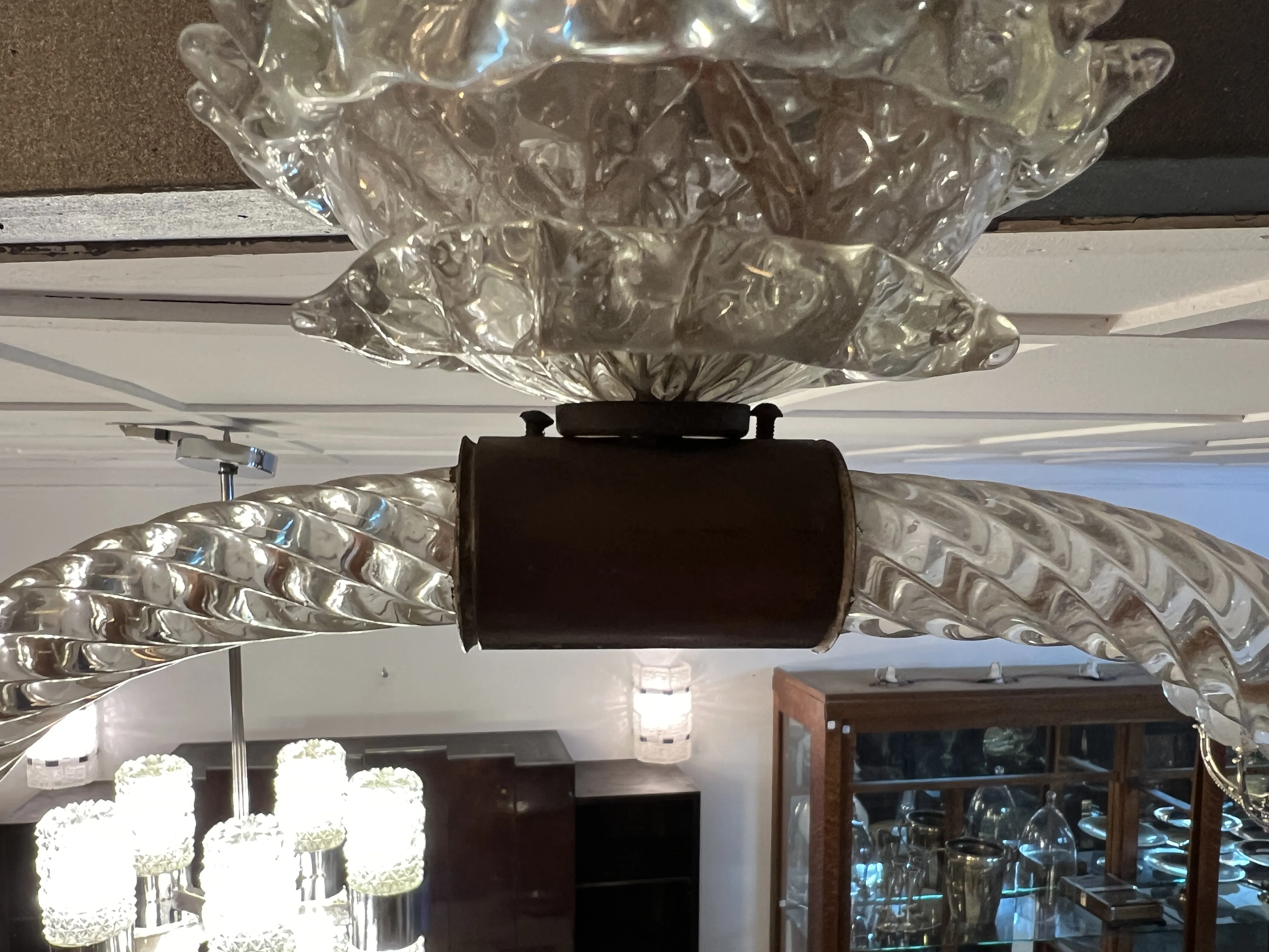 Vista de uma antiga lâmpada de teto Mazzega Murano com detalhes em vidro, luzes acesas ao fundo.