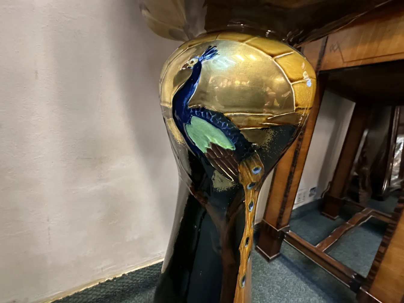 vase de plantes ancien orné d'un élégant motif de paon, décoré dans des tons dorés et bleus.