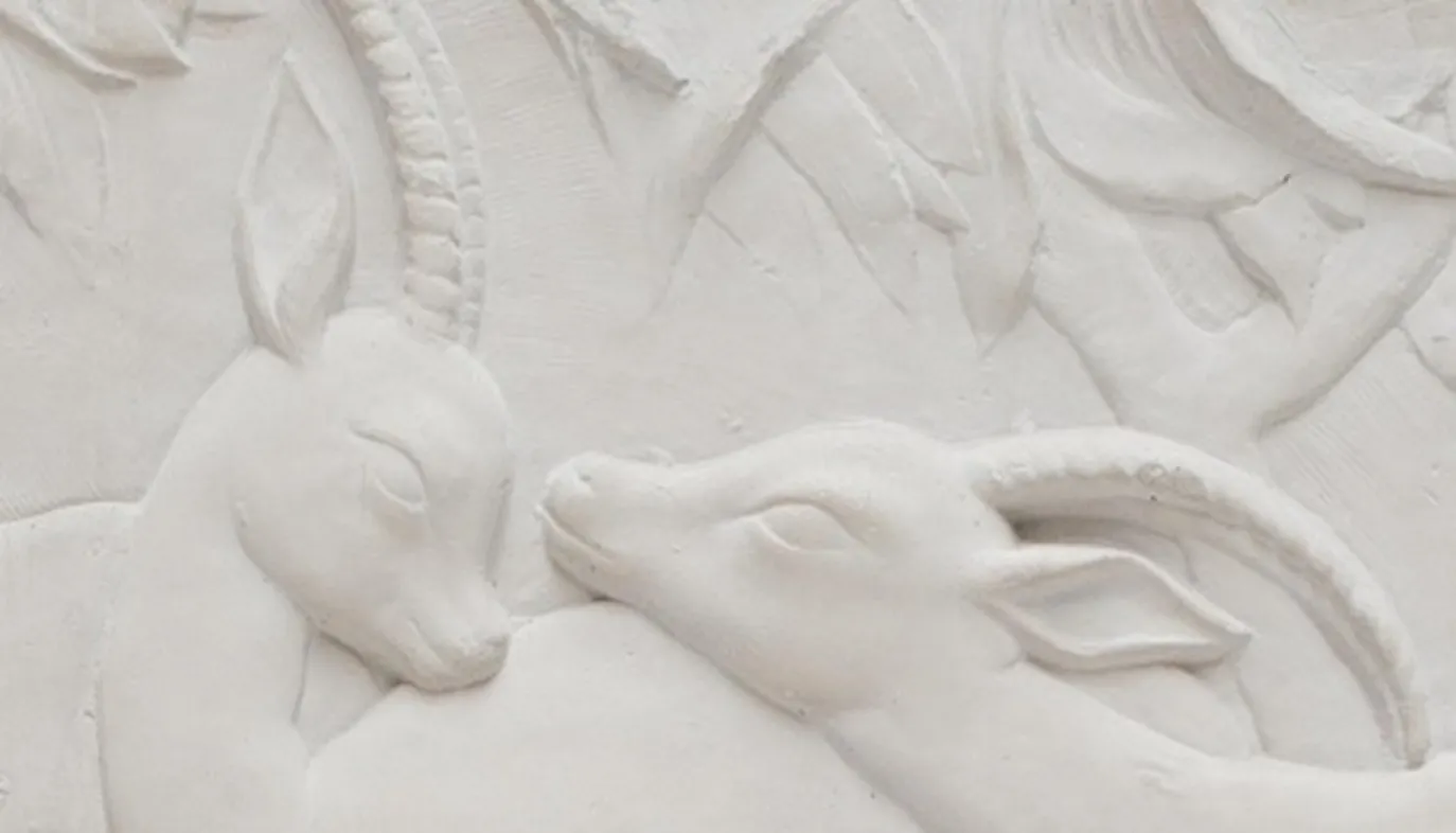 détail d'une plaque murale ancienne avec des reliefs d'animaux en blanc