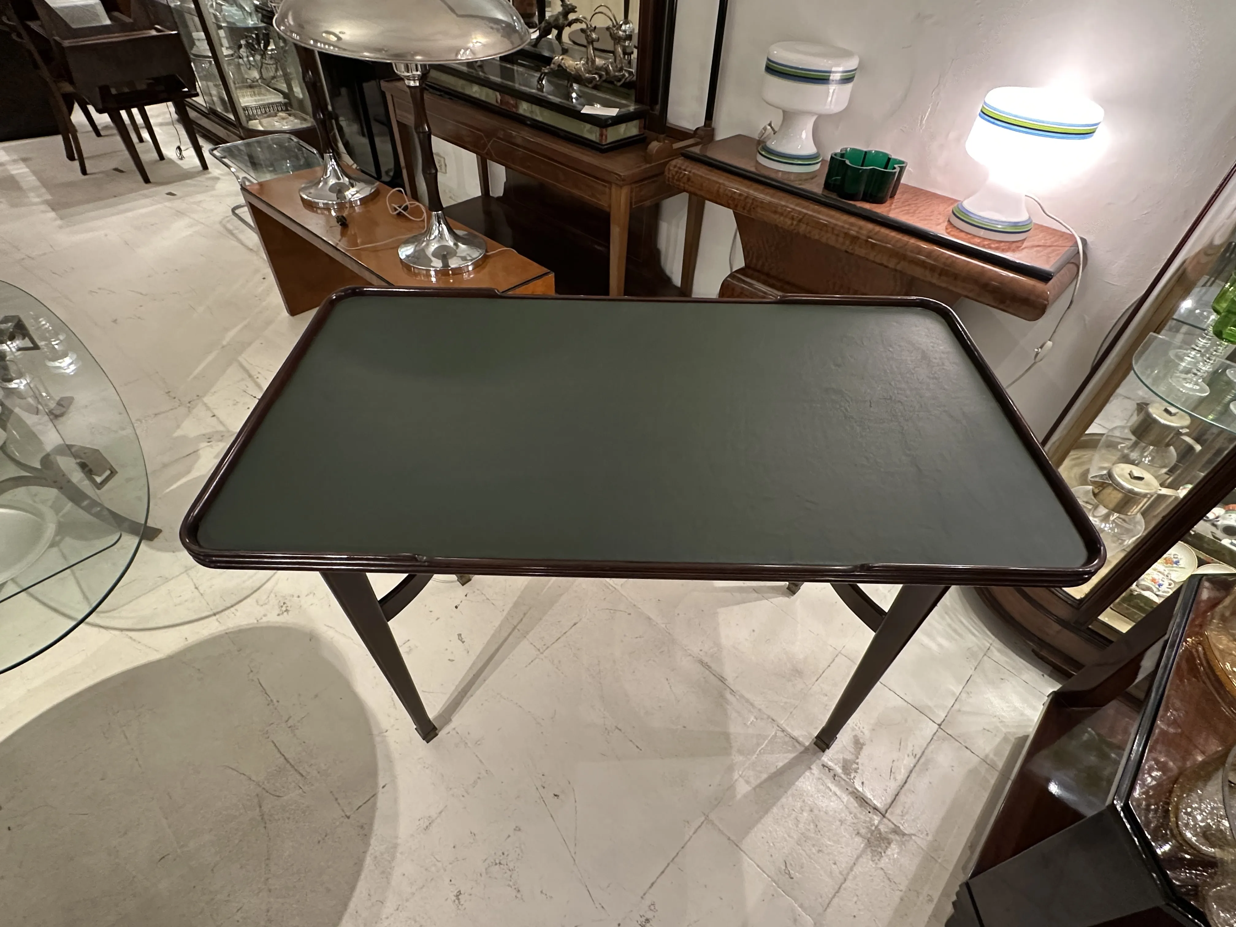 mesa de comedor antigua para 4 personas, rodeada de lámparas y vitrinas.