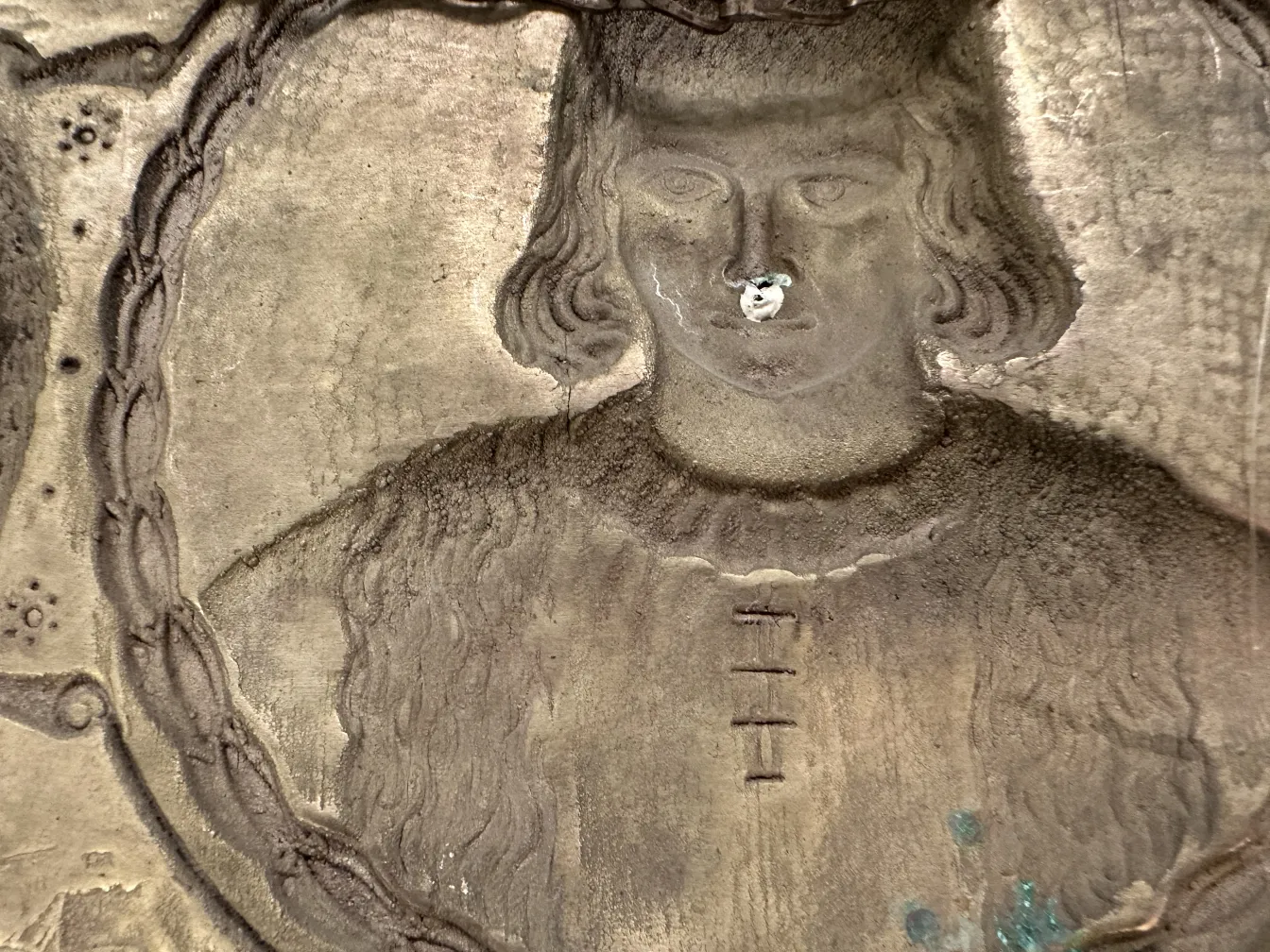 Antigua placa de pared con imagen de Cristóbal Colón, detalles visibles, fondo ligero.