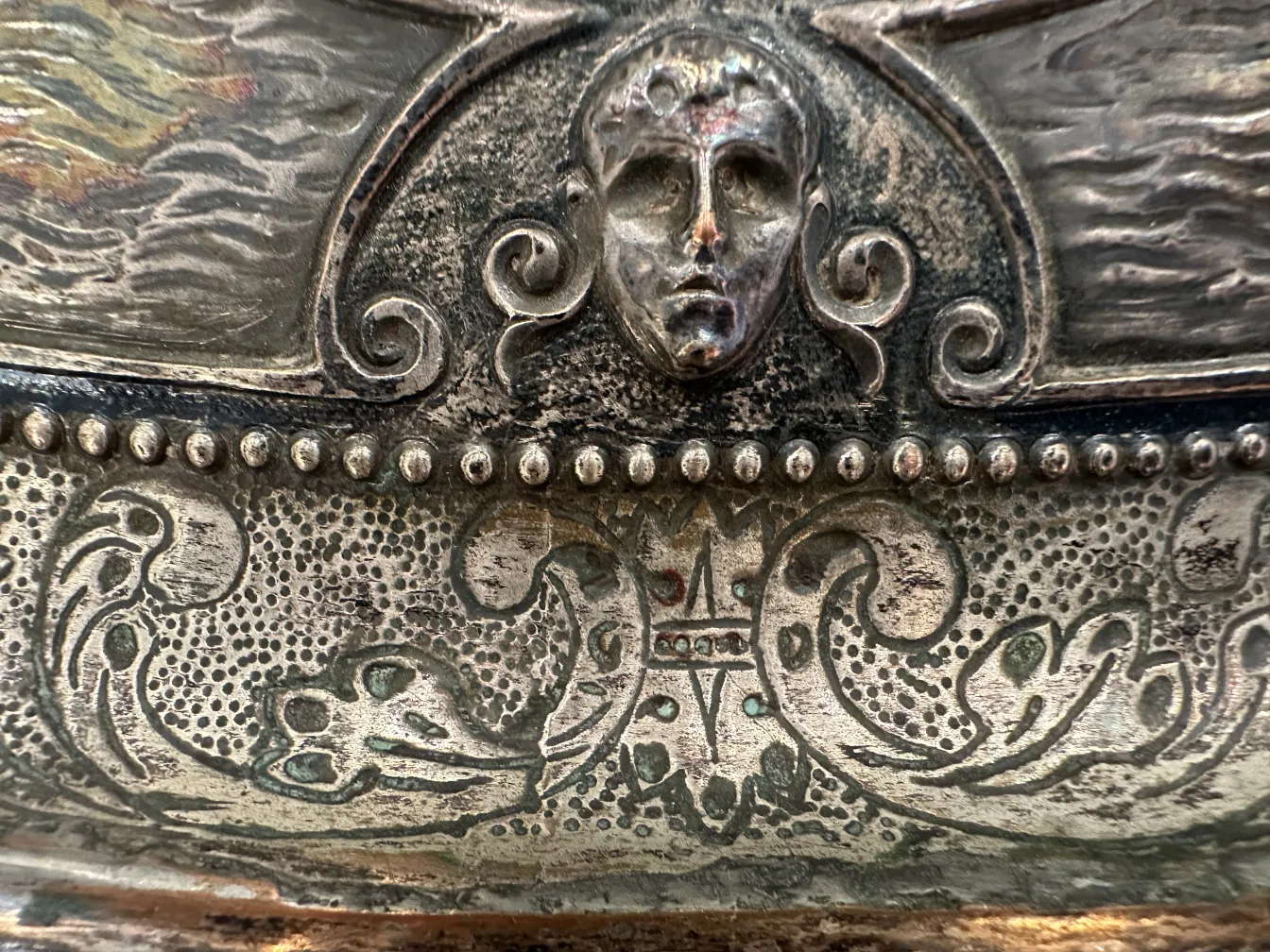 detail einer antiken wandplatte mit einem gesicht und geschwungenem design