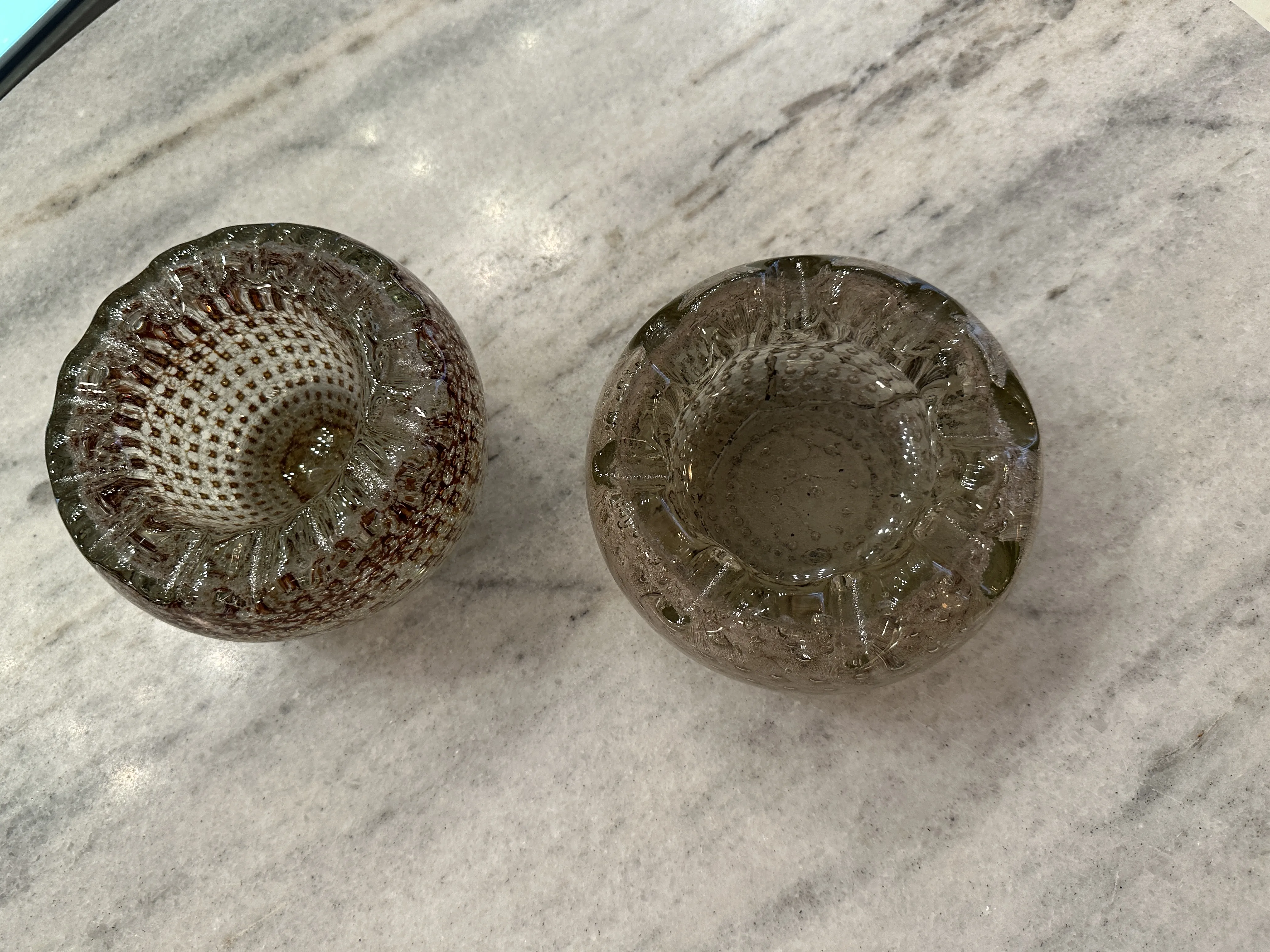 deux anciens cristaux de murano avec des formes arrondies en tons bruns, sur une surface claire.