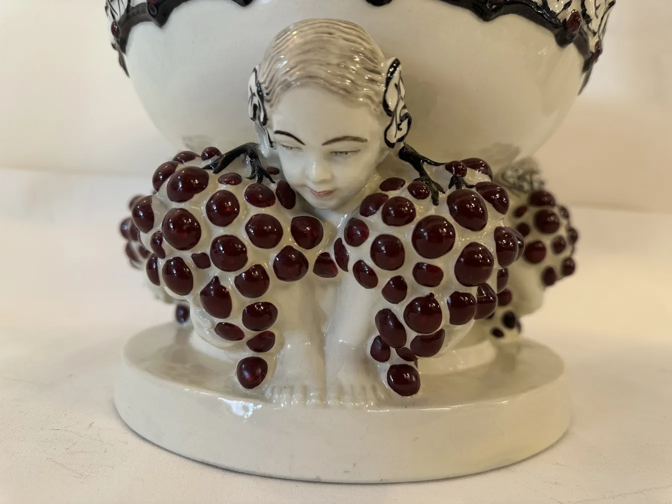 Antica figura in ceramica con decorazione di uva e volto