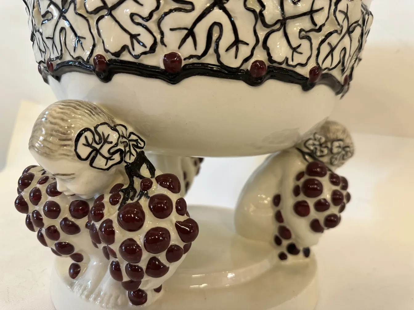 ceramica antigua con figuras sosteniendo uvas, detalles en blanco y negro