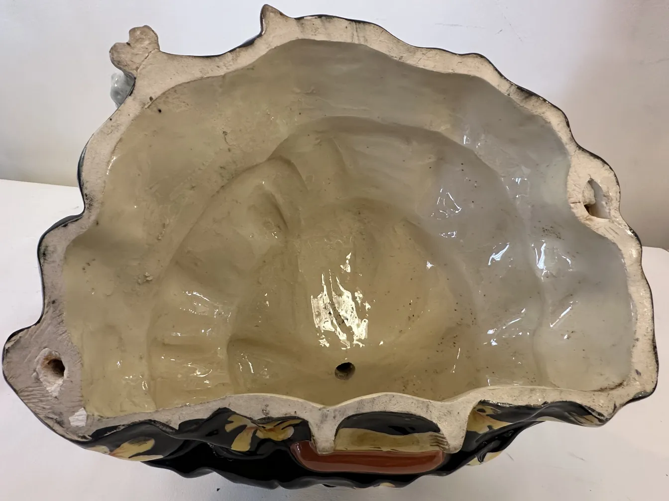 Antica ceramica con forma irregolare e decorazioni colorate.