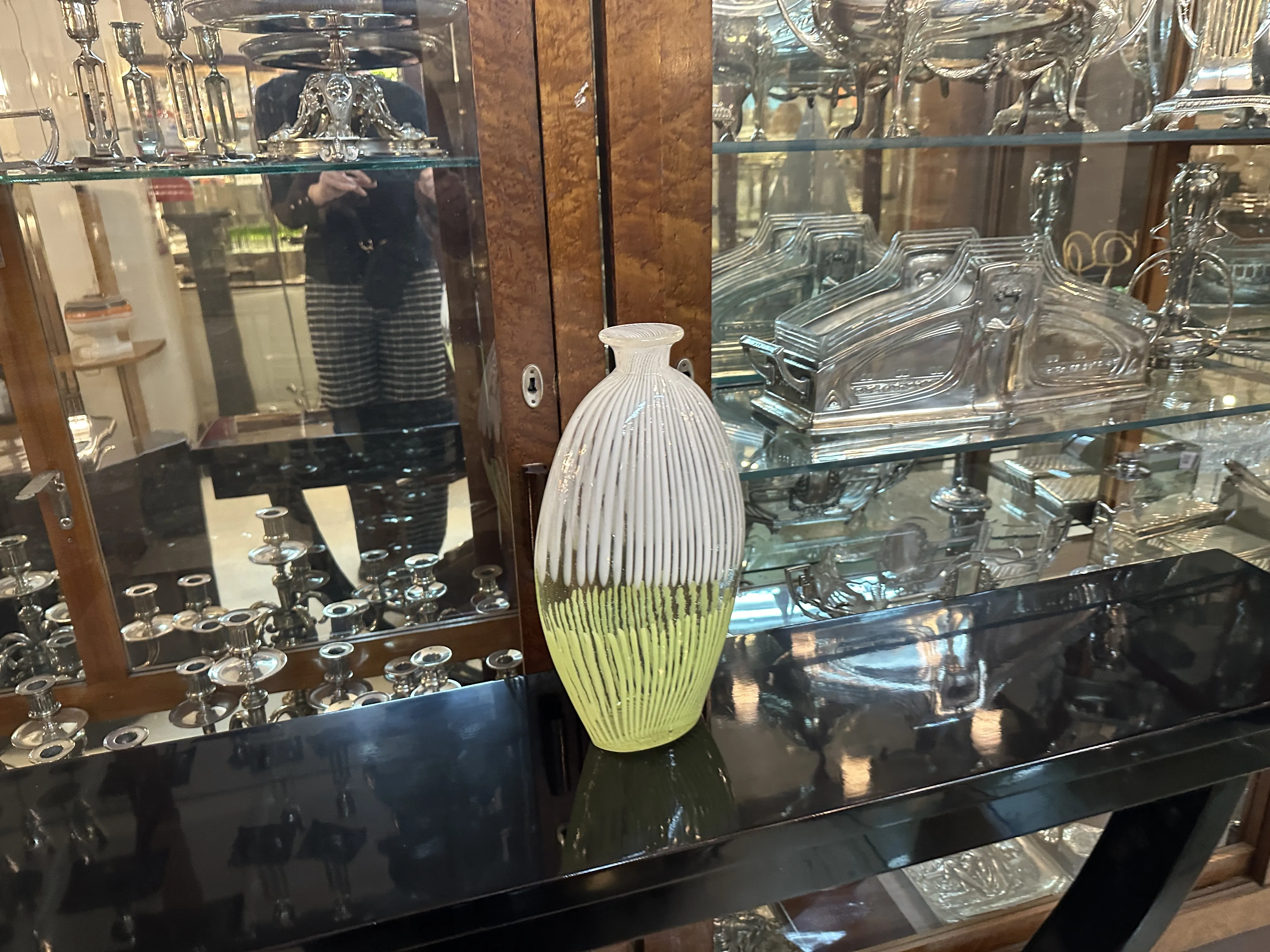 古董穆拉诺花瓶上有黄色和白色的图案，背景是金属和木制物品