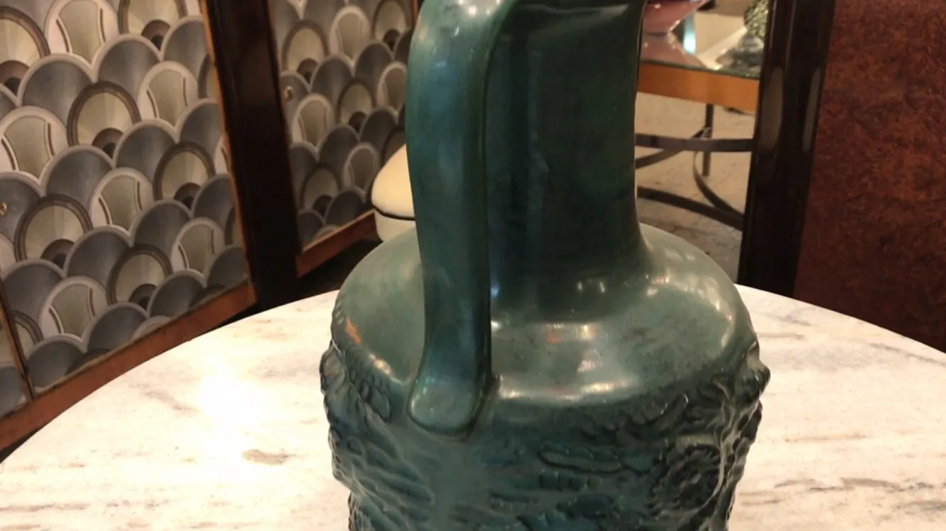 Una antigua cerámica con forma estilizada y detalles decorativos en un ambiente decorativo.