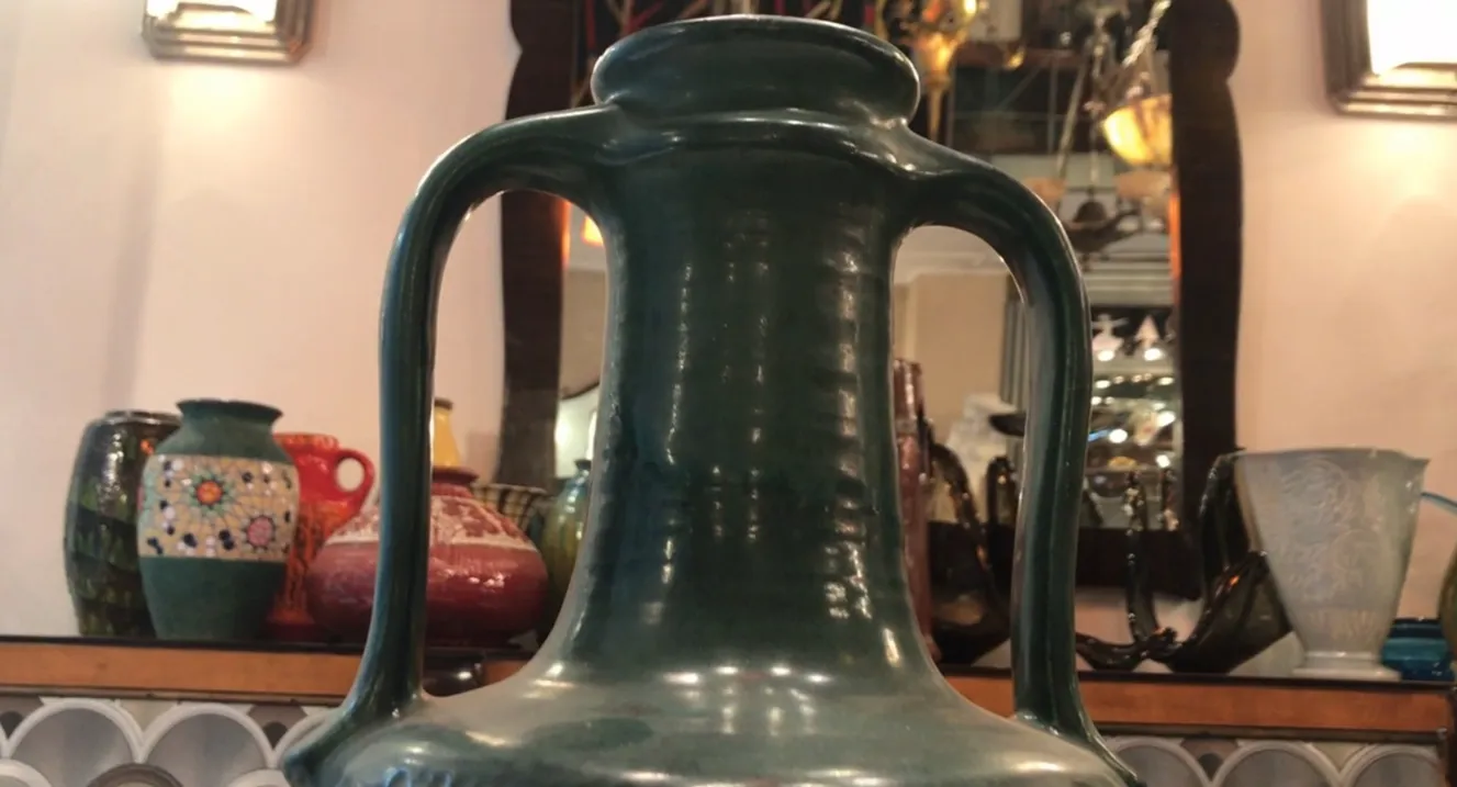 large antique ceramic jug with decorative details, background with other pieces