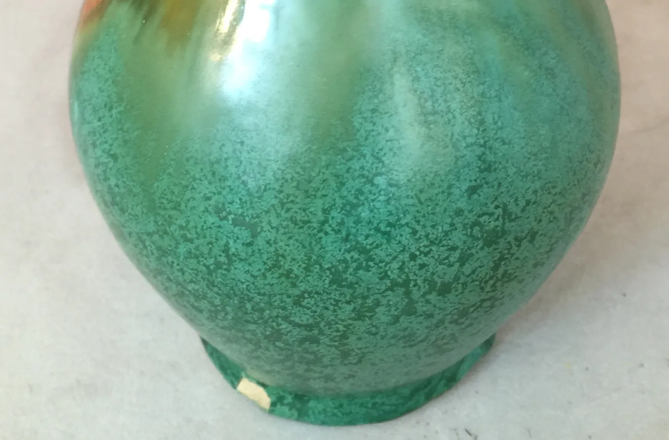 Vaso antico in ceramica con tonalità verdi e arancioni e dettagli decorativi unici