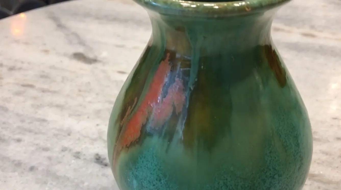 Vaso antico in ceramica con tonalità verdi e arancioni e dettagli decorativi unici