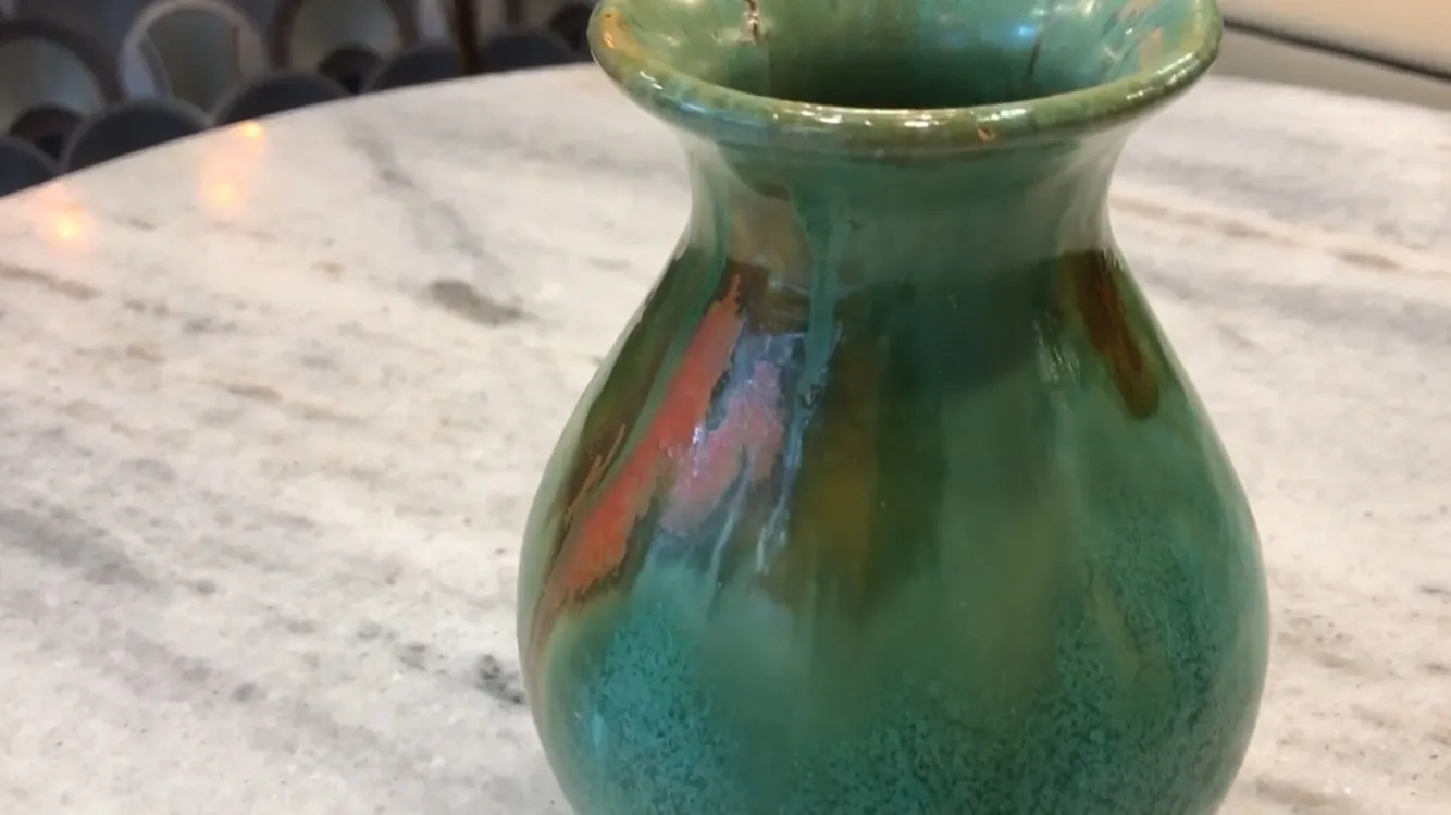 Vaso antico in ceramica con tonalità verdi e arancioni e dettagli decorativi unici