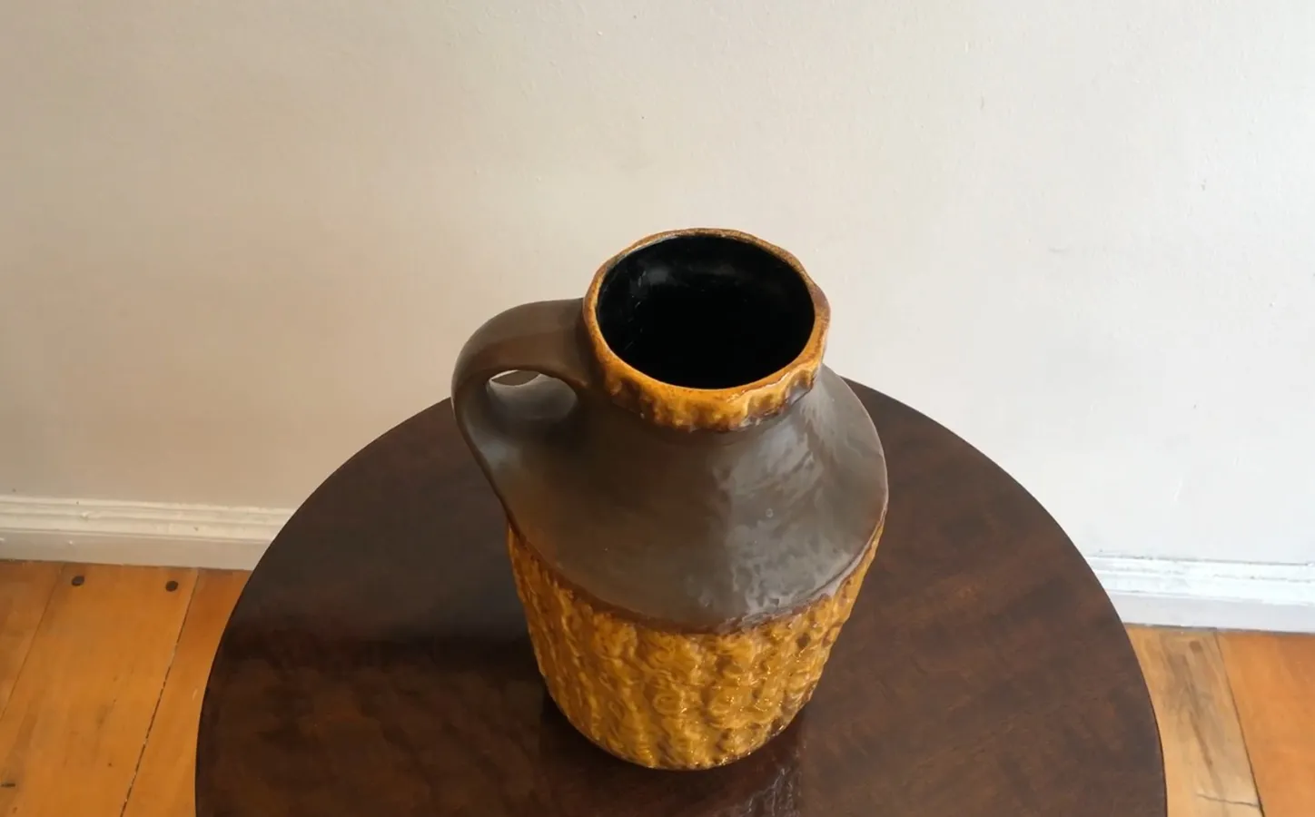 Una vecchia ceramica con design testurizzato in toni marroni e gialli, su un tavolo.