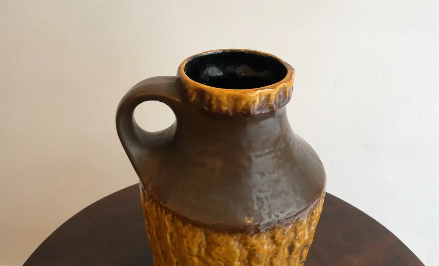 Antigua cerámica con forma de jarra y detalles rugosos; ambiente neutro.