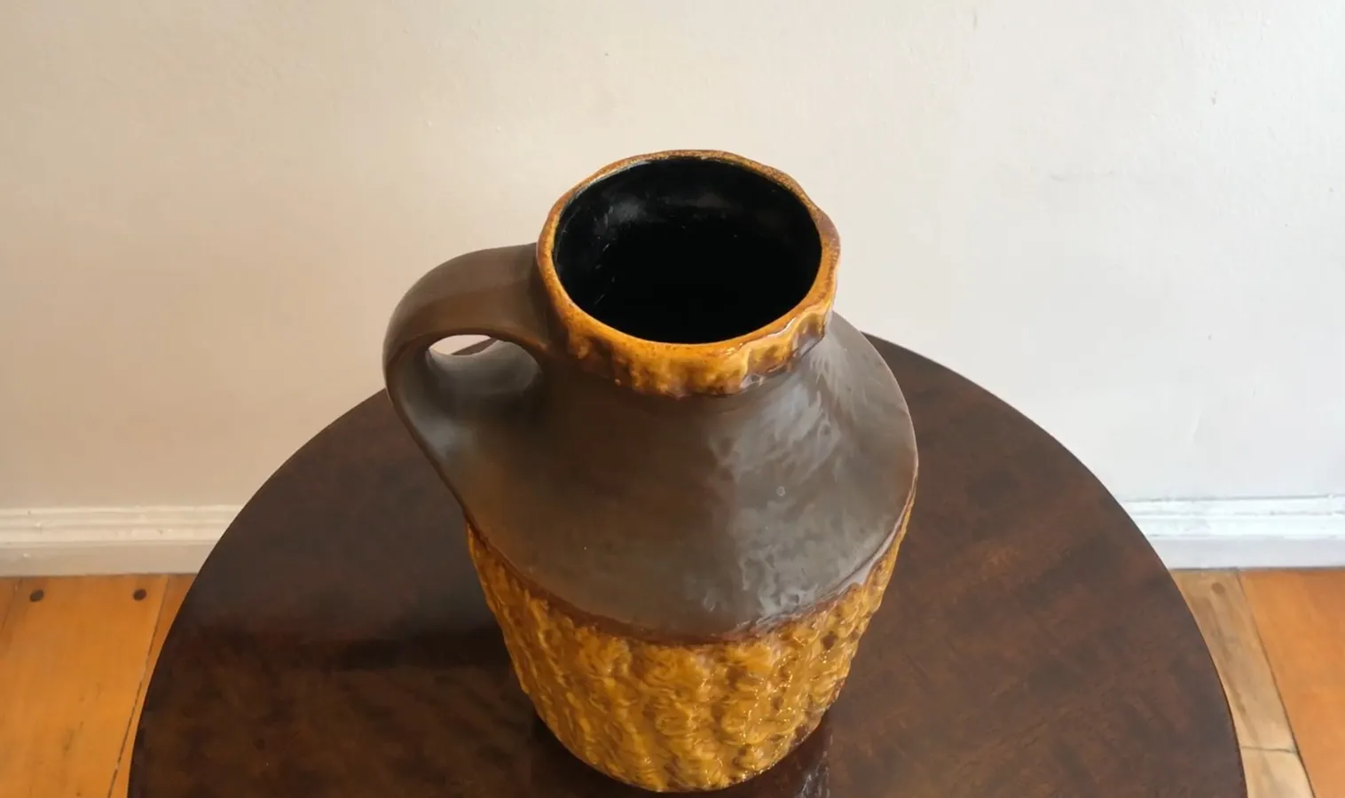 Giara di ceramica antica con motivi testurizzati in marrone e giallo.