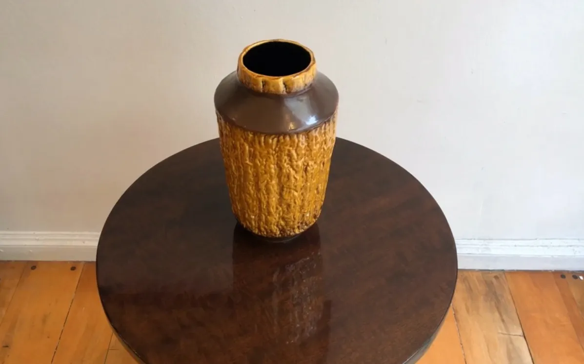 Vaso antico in ceramica color ambra con texture ruvida.