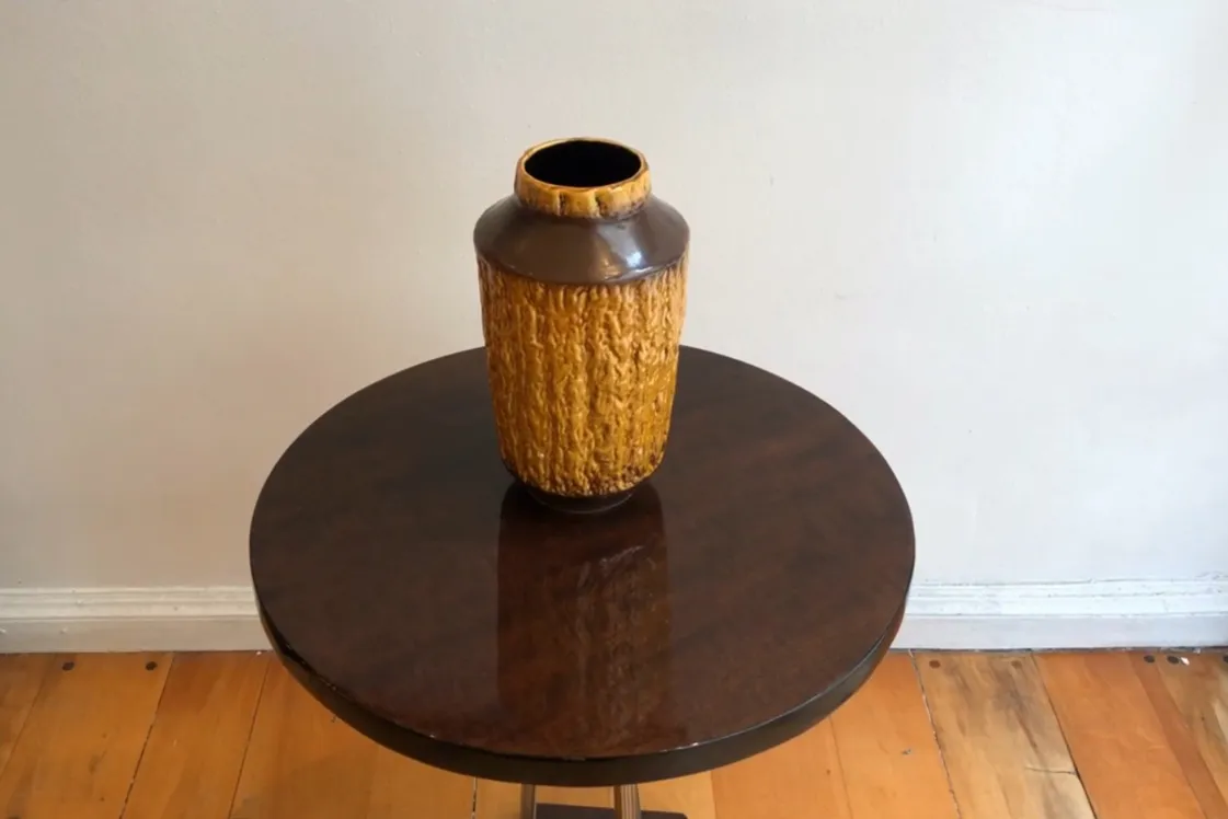 Vaso antigo de cerâmica em cor âmbar com textura rugosa.
