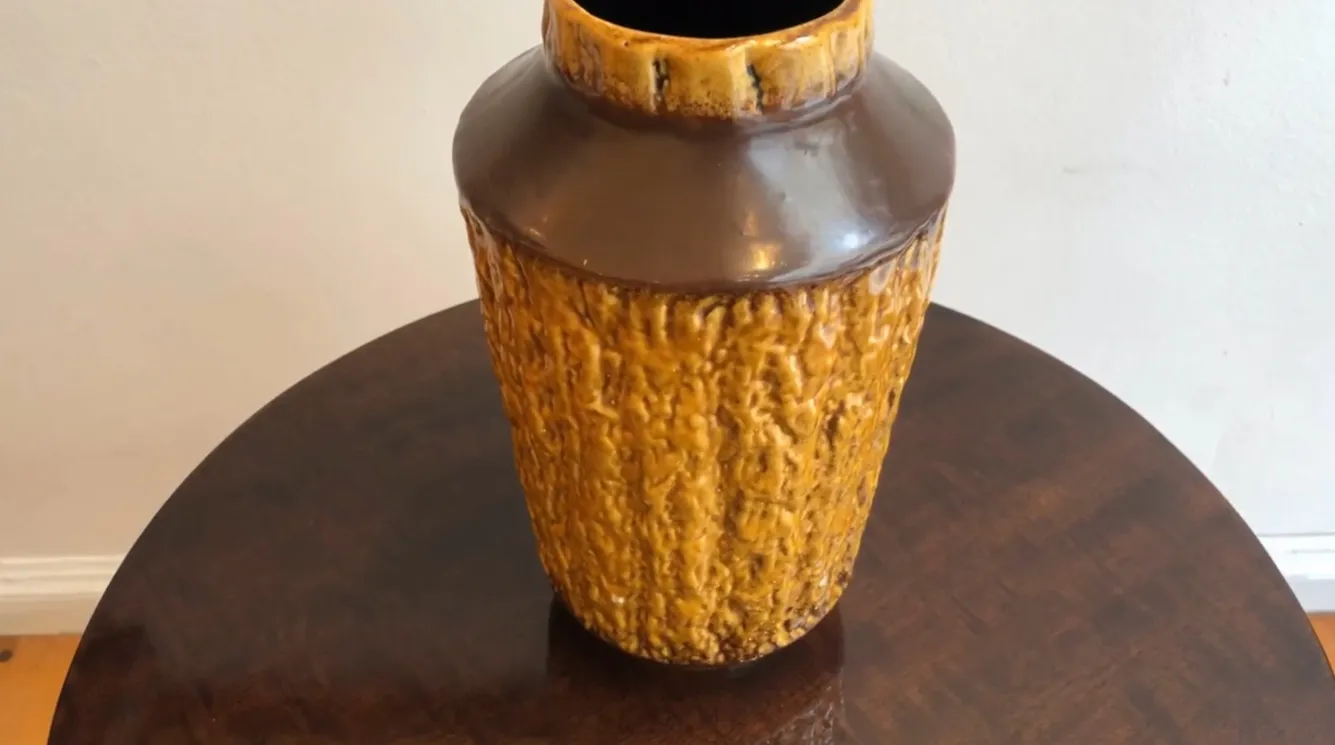 Vaso antico in ceramica color ambra con texture ruvida.