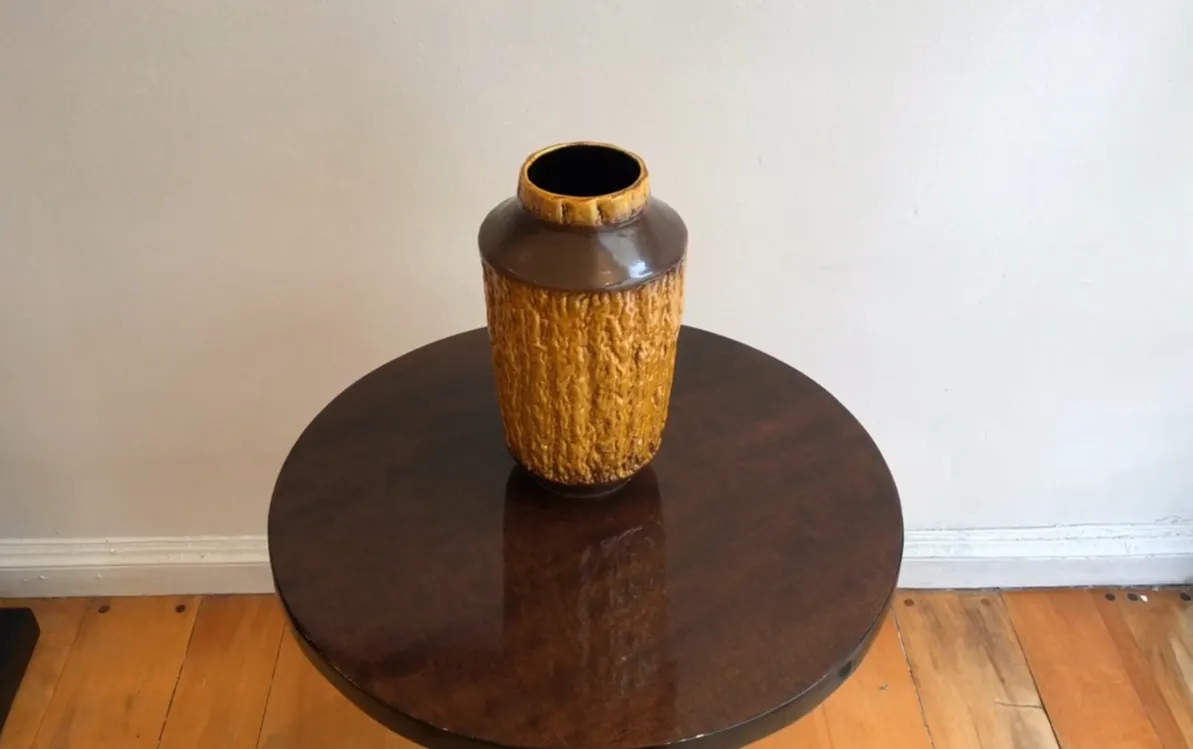 Vaso antico in ceramica color ambra con texture ruvida.