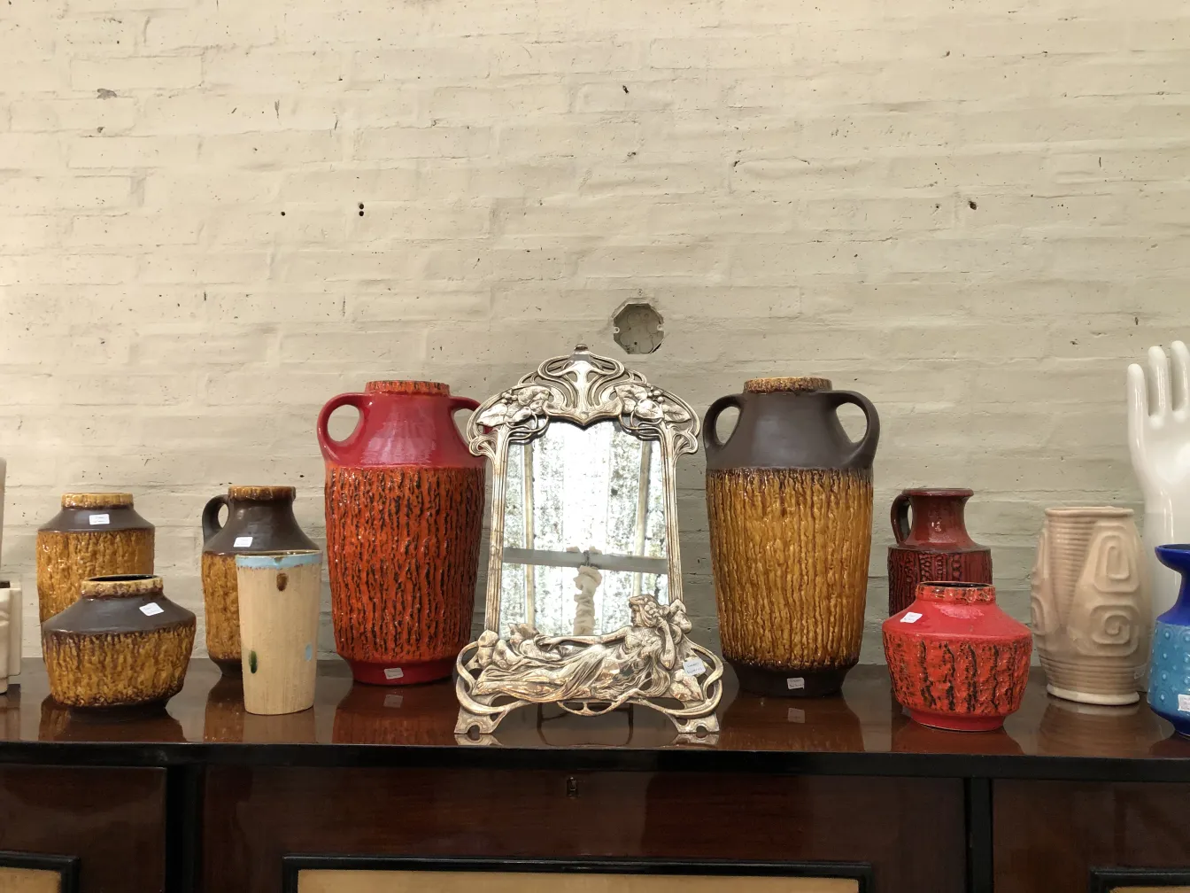 Variedade de jarras antigas de cerâmica artesanal em vermelho, laranja e marrom.