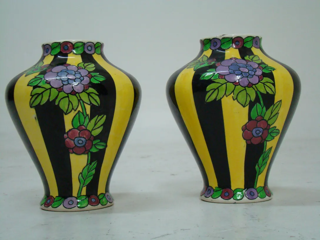 Two antique ceramic vases with floral design, vibrant colors, and black and yellow stripes.